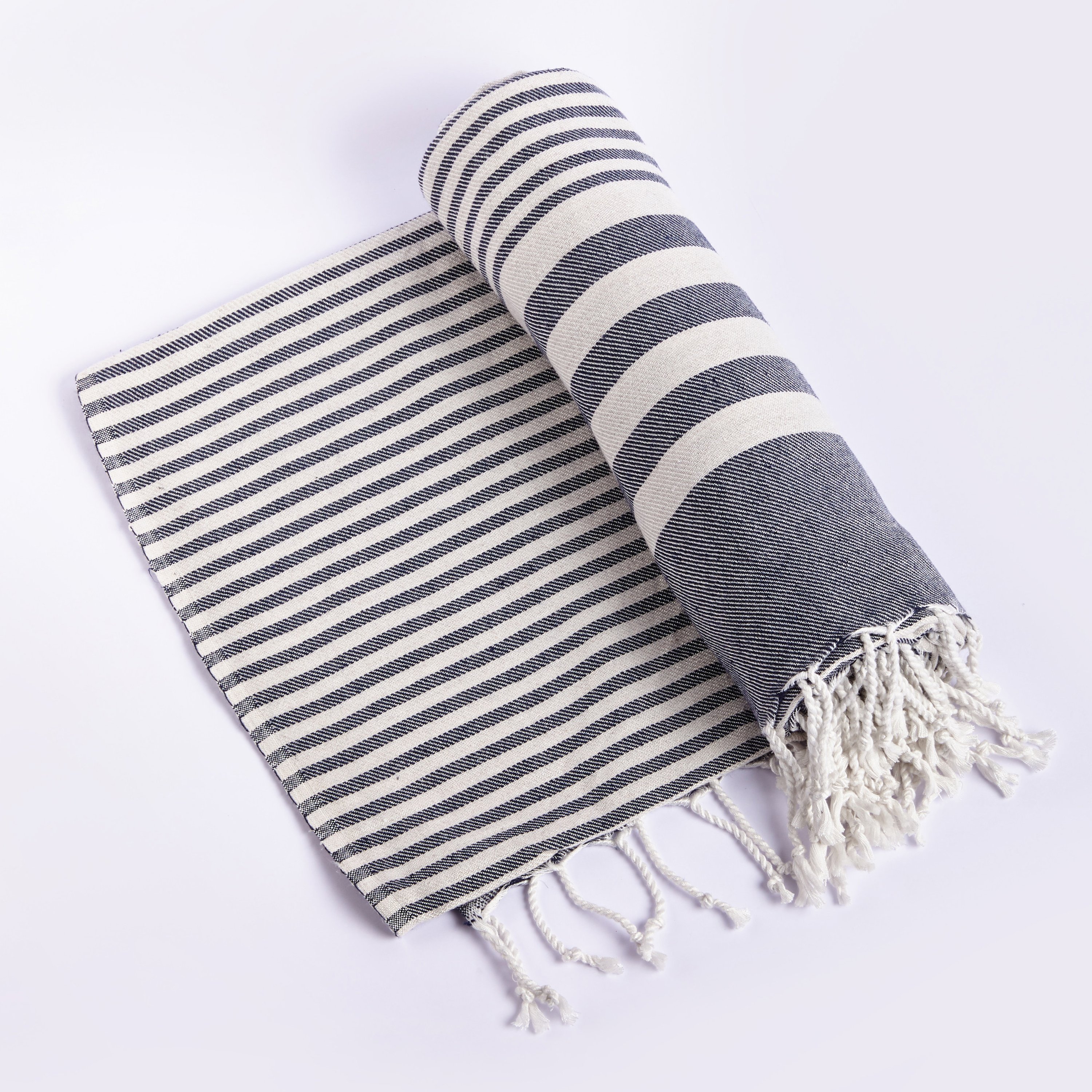 Fethiye Striped Blanket Throw in Blue with navy stripes, showcasing its soft texture and compact design, perfect for indoor and outdoor use.