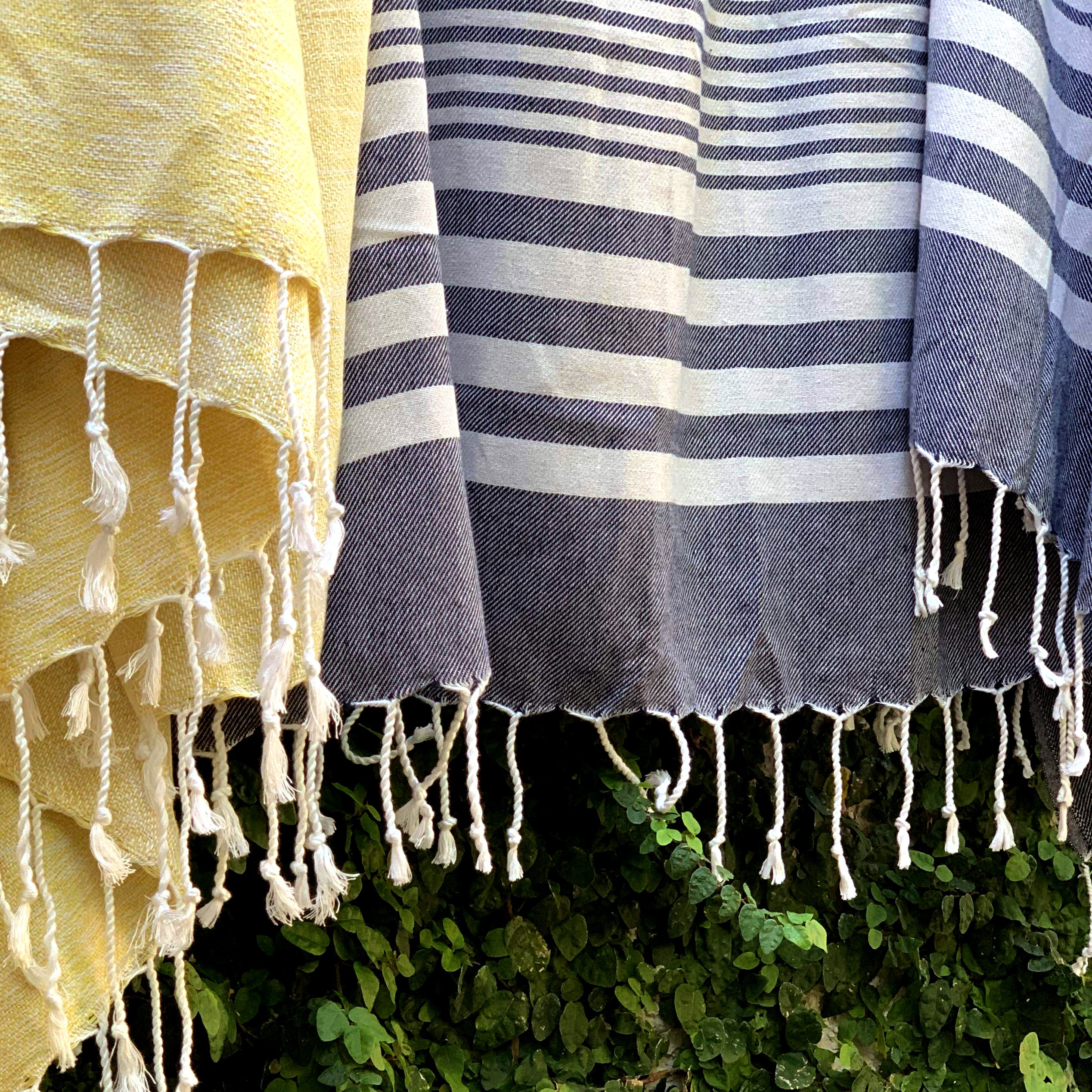Fethiye Striped Blanket Throw in Blue with navy stripes, showcasing its soft texture and compact design, perfect for indoor and outdoor use.