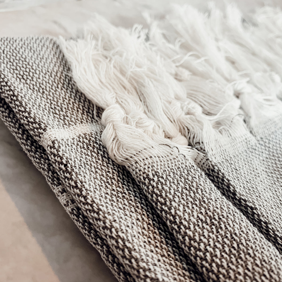 Haley Stripe Towel made from 100% Turkish cotton, featuring decorative tassels and available in light gray and dark gray stripes.