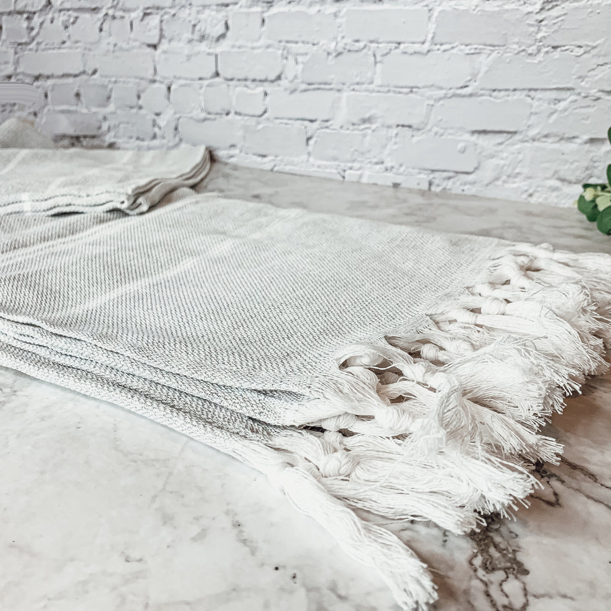 Haley Stripe Towel made from 100% Turkish cotton, featuring decorative tassels and available in light gray and dark gray stripes.