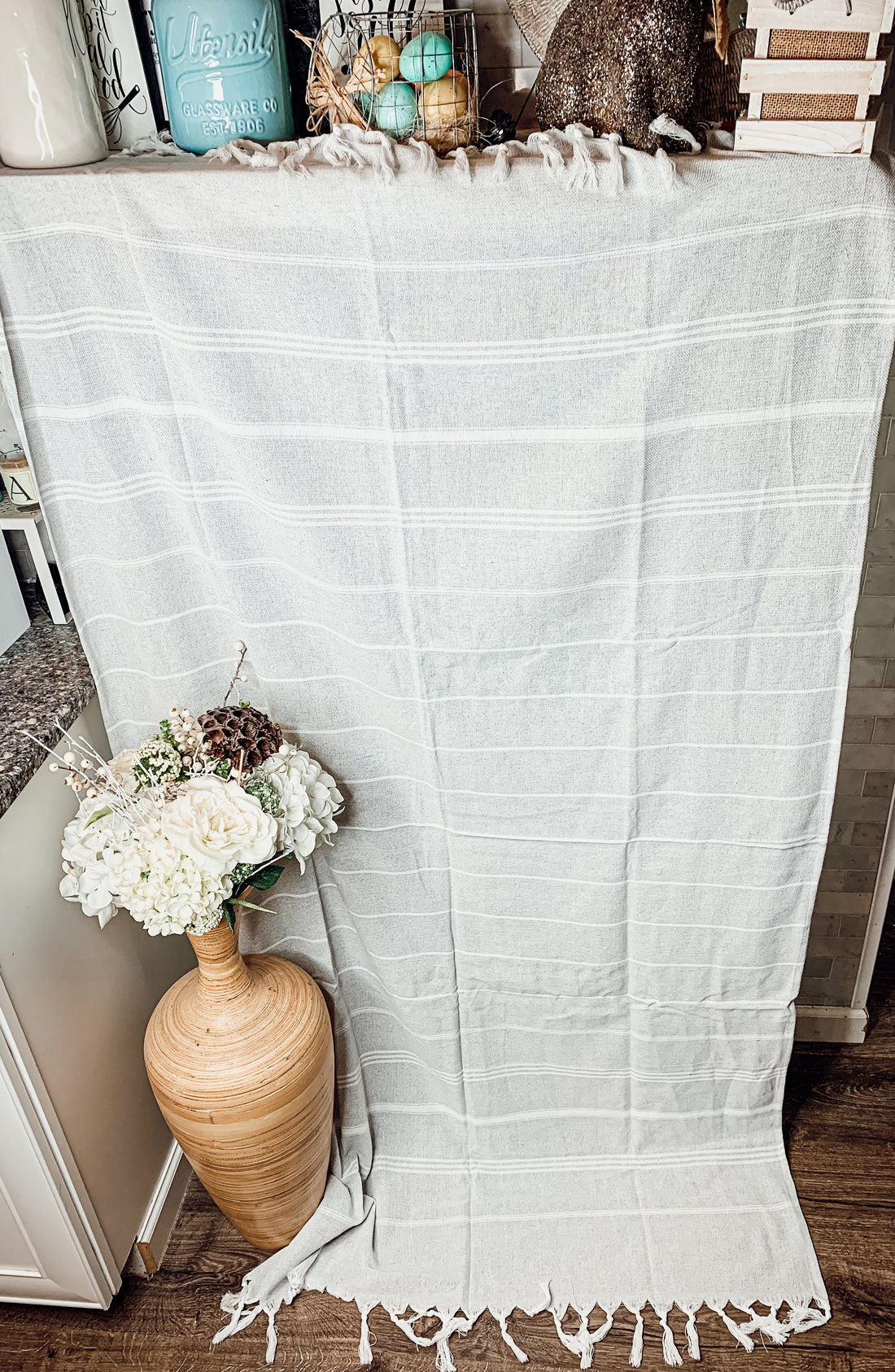 Haley Stripe Towel made from 100% Turkish cotton, featuring decorative tassels and available in light gray and dark gray stripes.