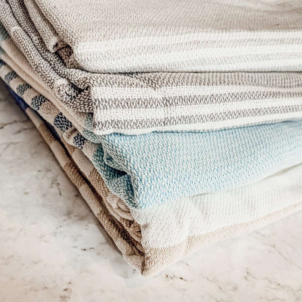 Haley Stripe Towel made from 100% Turkish cotton, featuring decorative tassels and available in light gray and dark gray stripes.