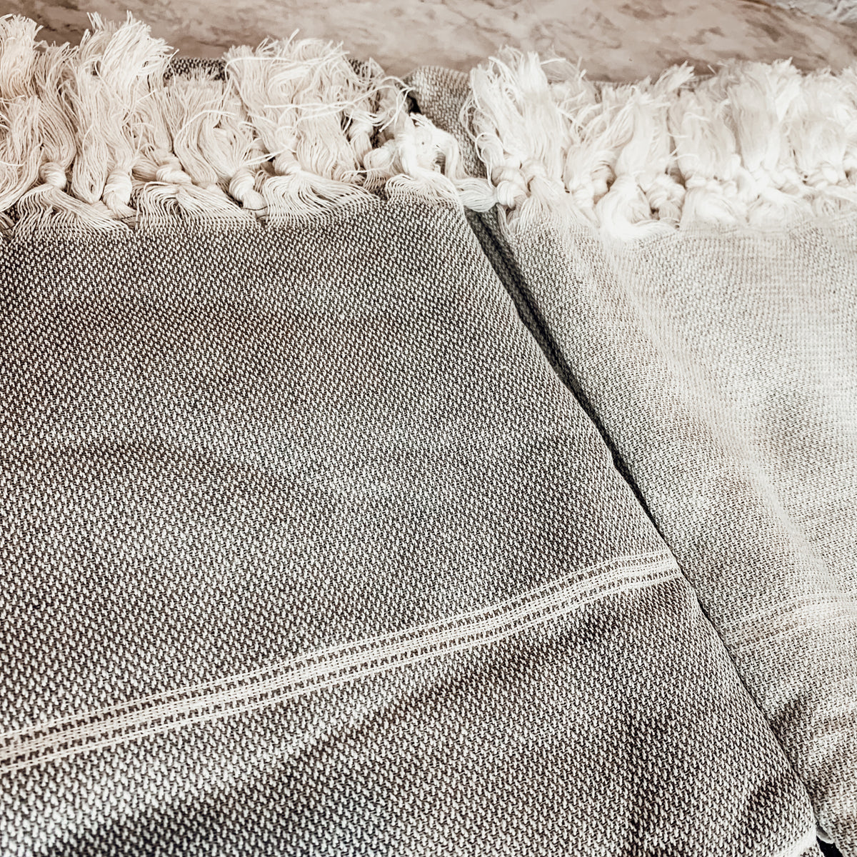 Haley Stripe Towel made from 100% Turkish cotton, featuring decorative tassels and available in light gray and dark gray stripes.