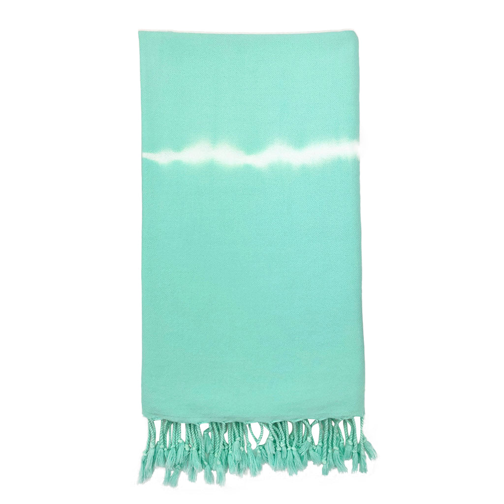 Mint Tie Dye Turkish Beach Towel displayed on a sandy beach, showcasing its vibrant colors and texture.