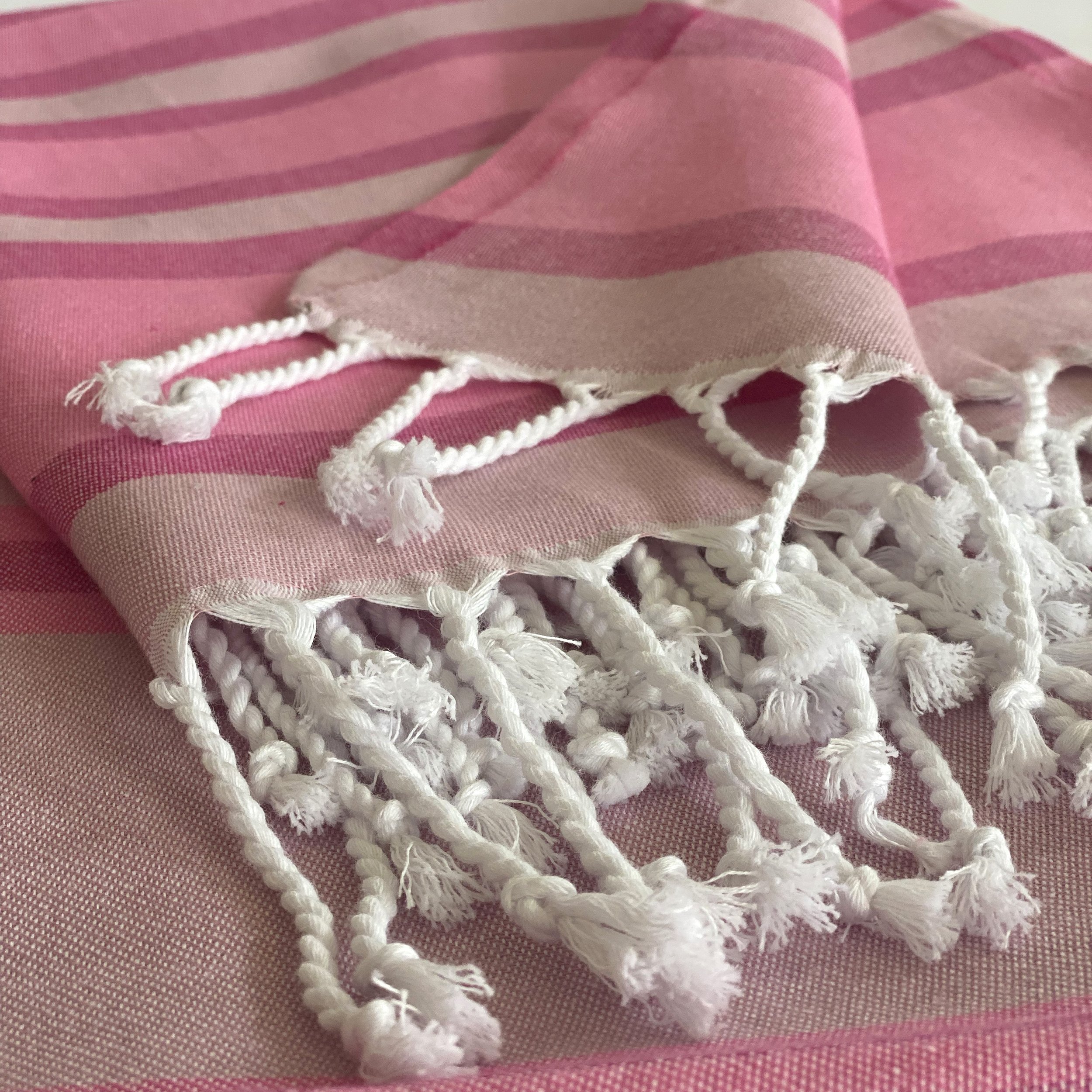 Samara Sustainable Turkish Towel in Pink with hand-tied tassels, showcasing its soft texture and eco-friendly design.