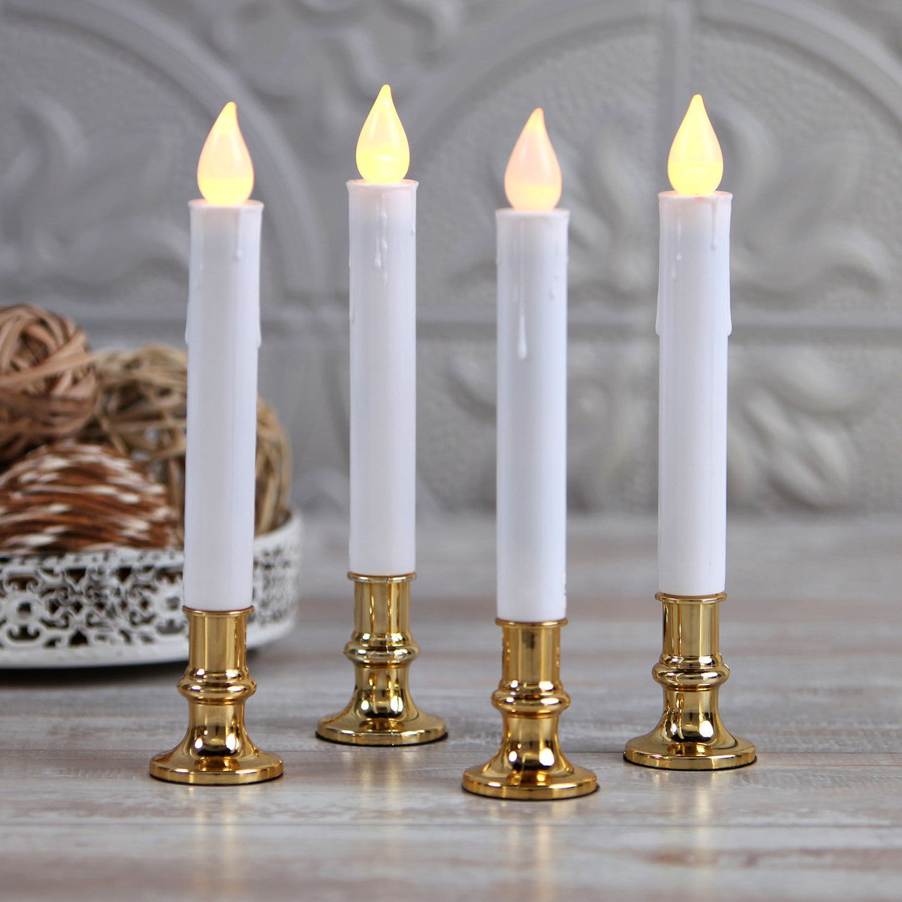 Three elegant white taper stick candles on a gold stand, designed for battery operation with a natural flame light color.