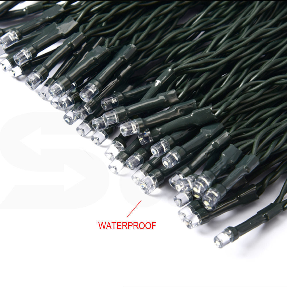 A long string of 500 LED solar-powered fairy lights glowing in a garden setting, showcasing their bright cool white illumination.