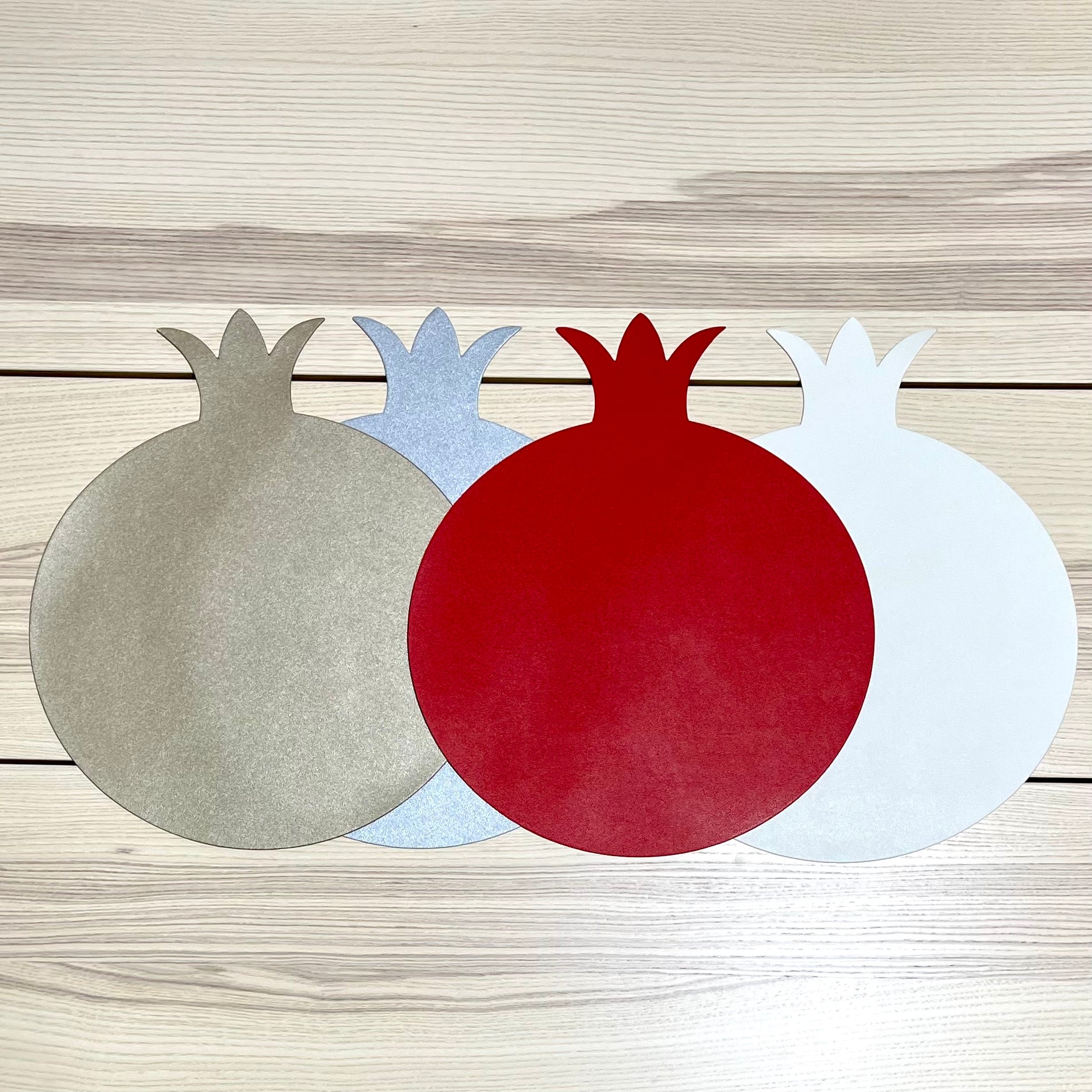 A set of six pomegranate-shaped placemats made from smooth faux leather in vibrant colors, perfect for festive dining.