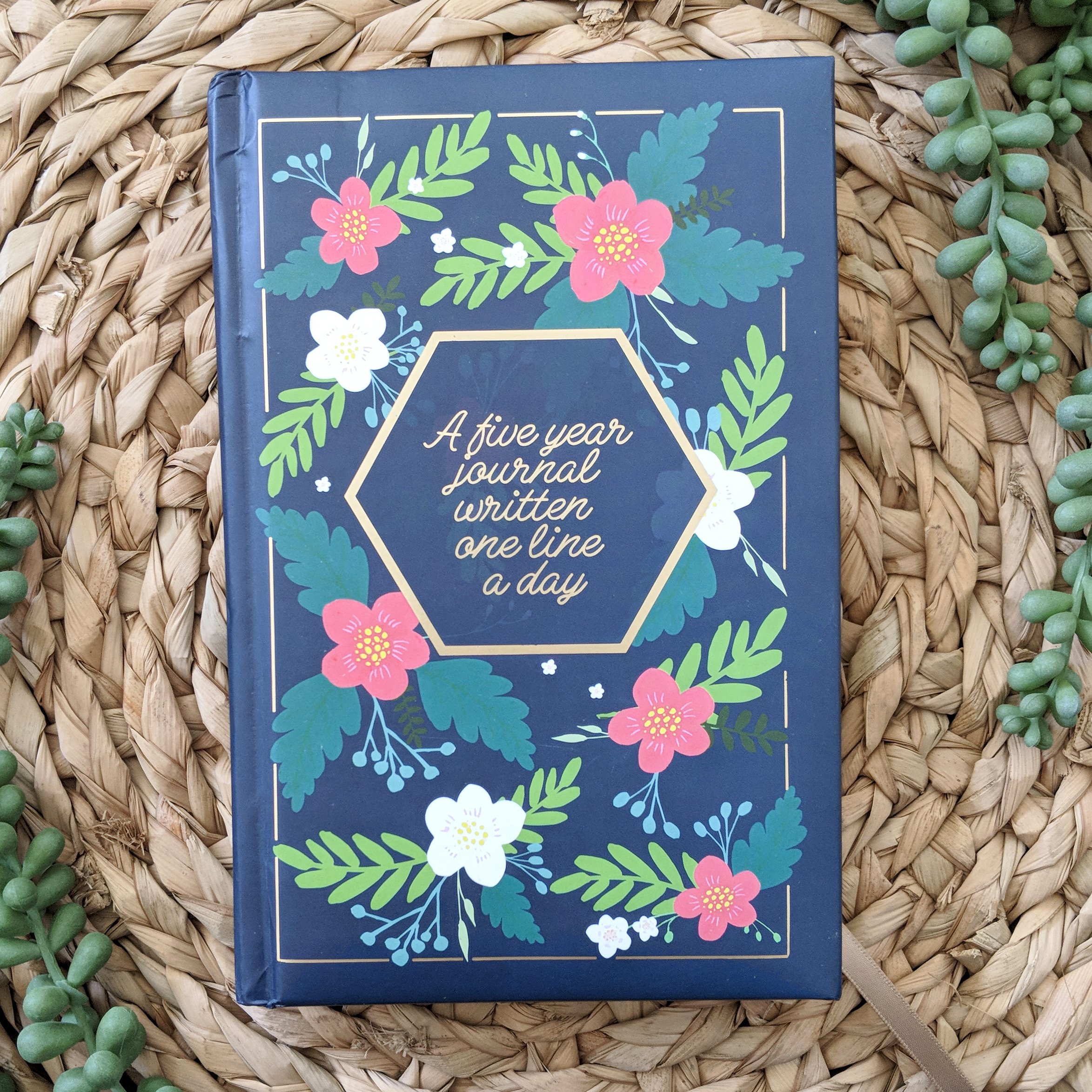 A beautiful navy floral five-year journal with gold accents, featuring a bookmark ribbon and gold foil edges, perfect for daily reflections.