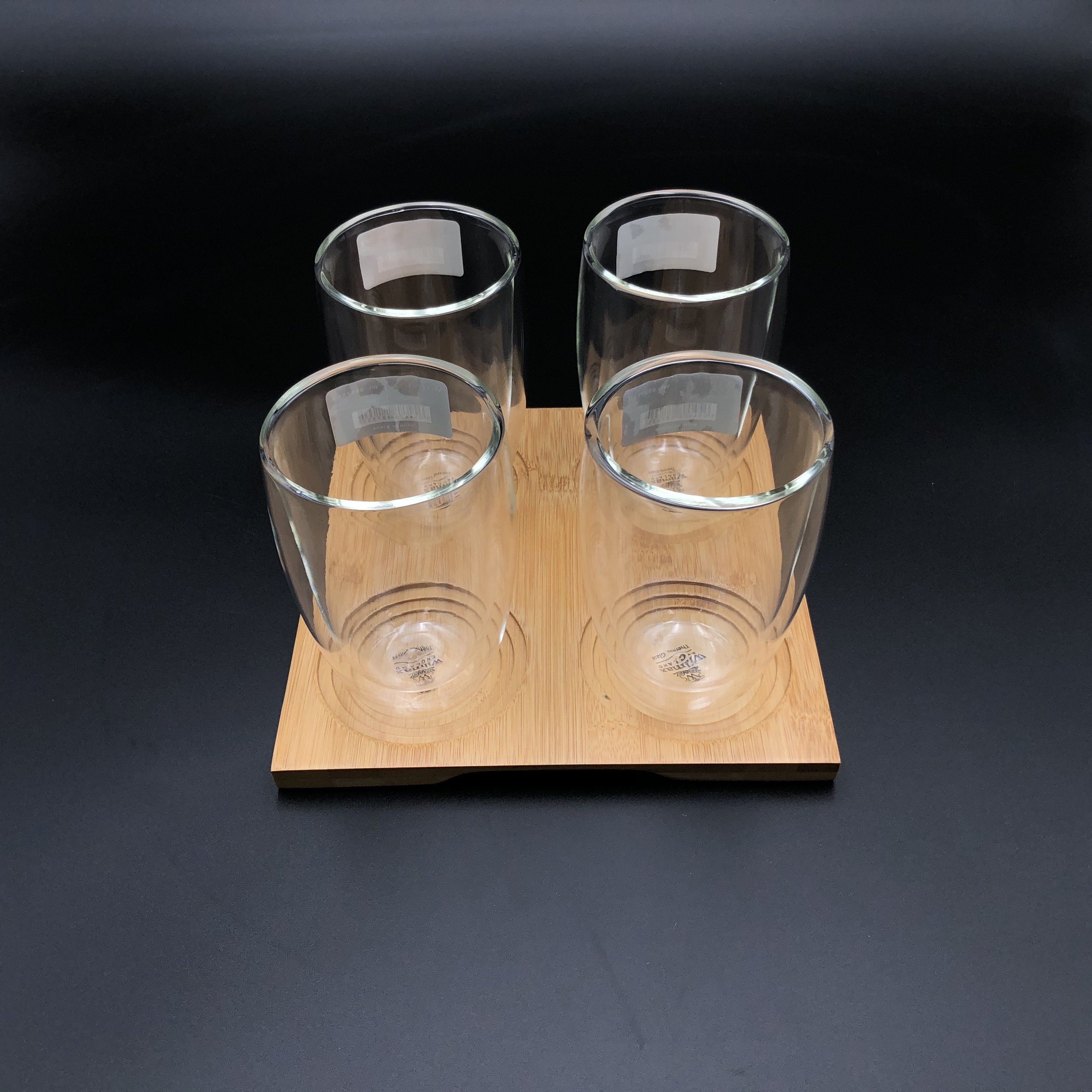 A stylish bamboo tray with four double-walled thermo glasses, showcasing an elegant dining presentation.