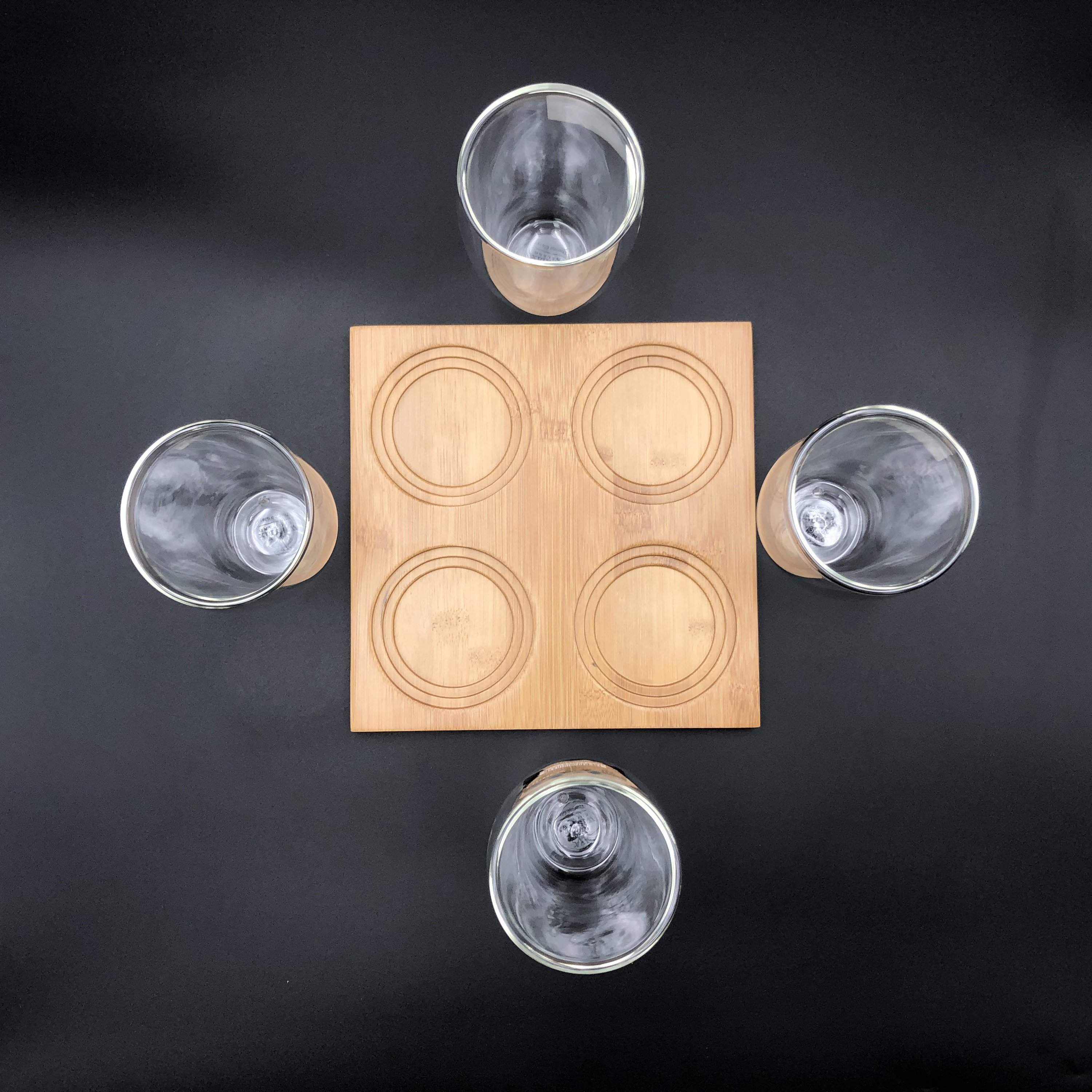 A stylish bamboo tray with four double-walled thermo glasses, showcasing an elegant dining presentation.