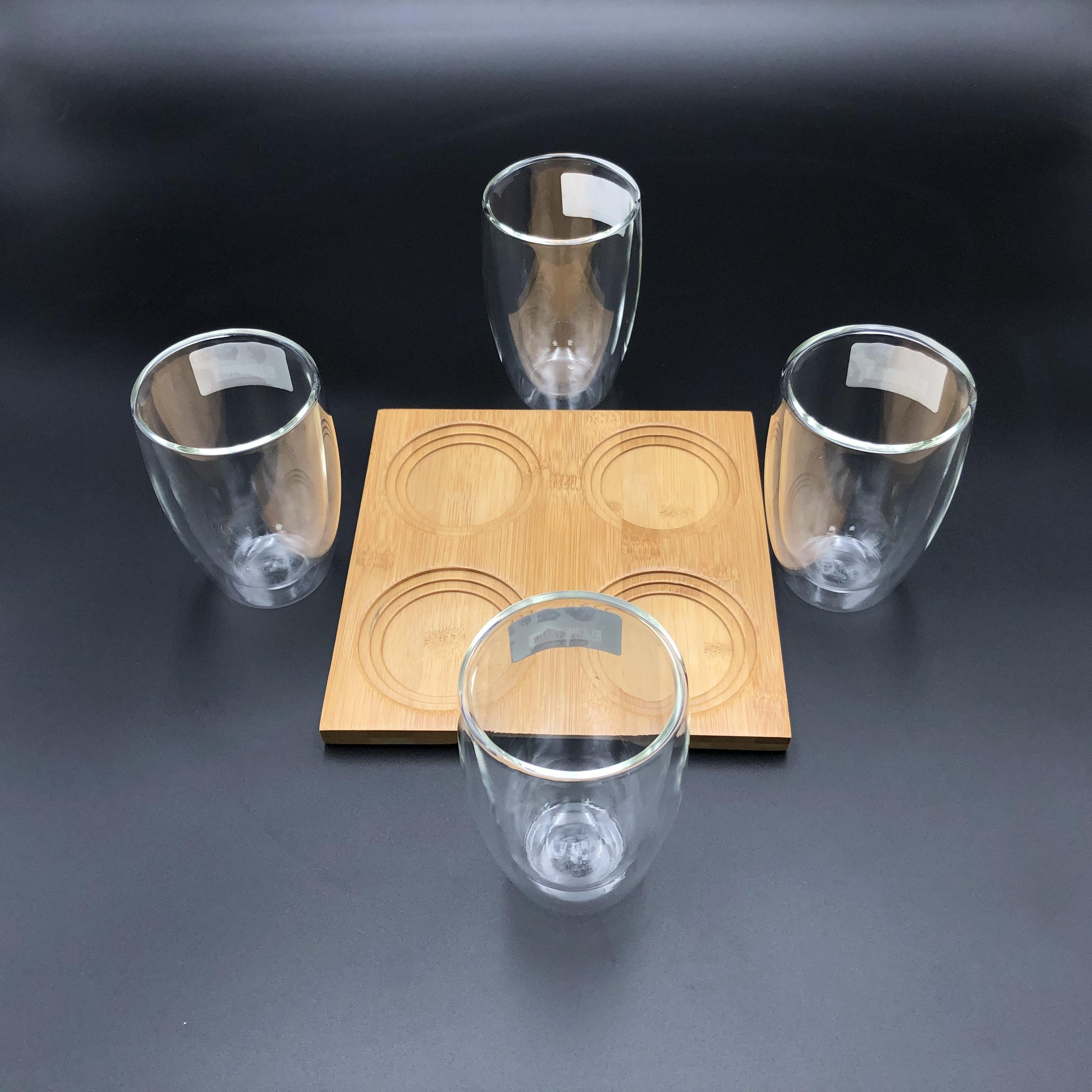 A stylish bamboo tray with four double-walled thermo glasses, showcasing an elegant dining presentation.