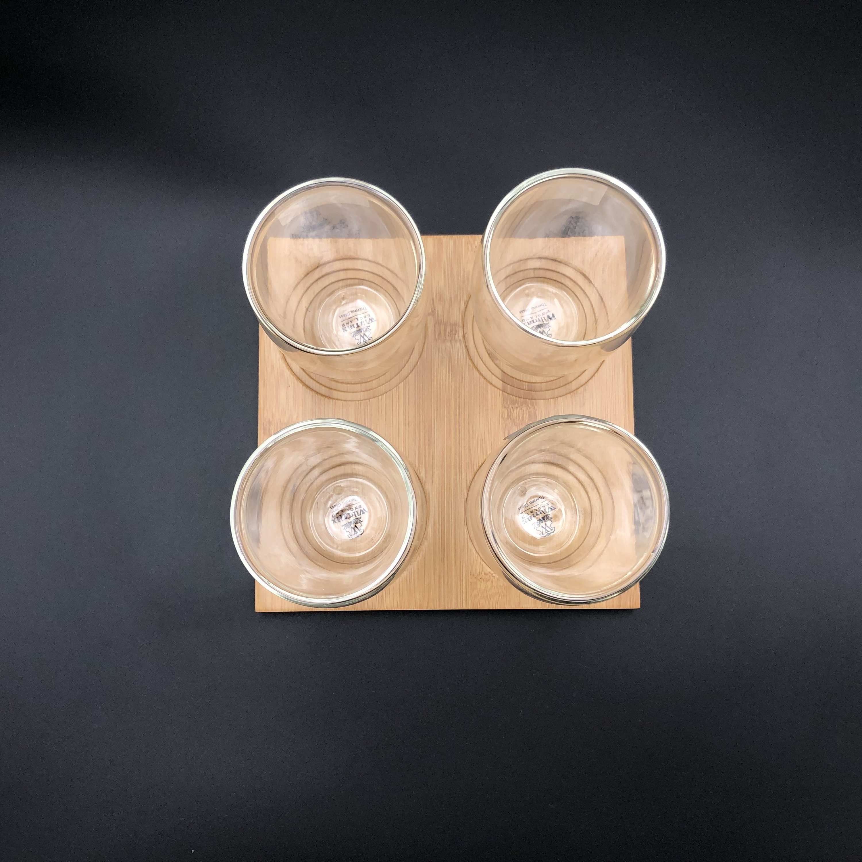 A stylish bamboo tray with four double-walled thermo glasses, showcasing an elegant dining presentation.