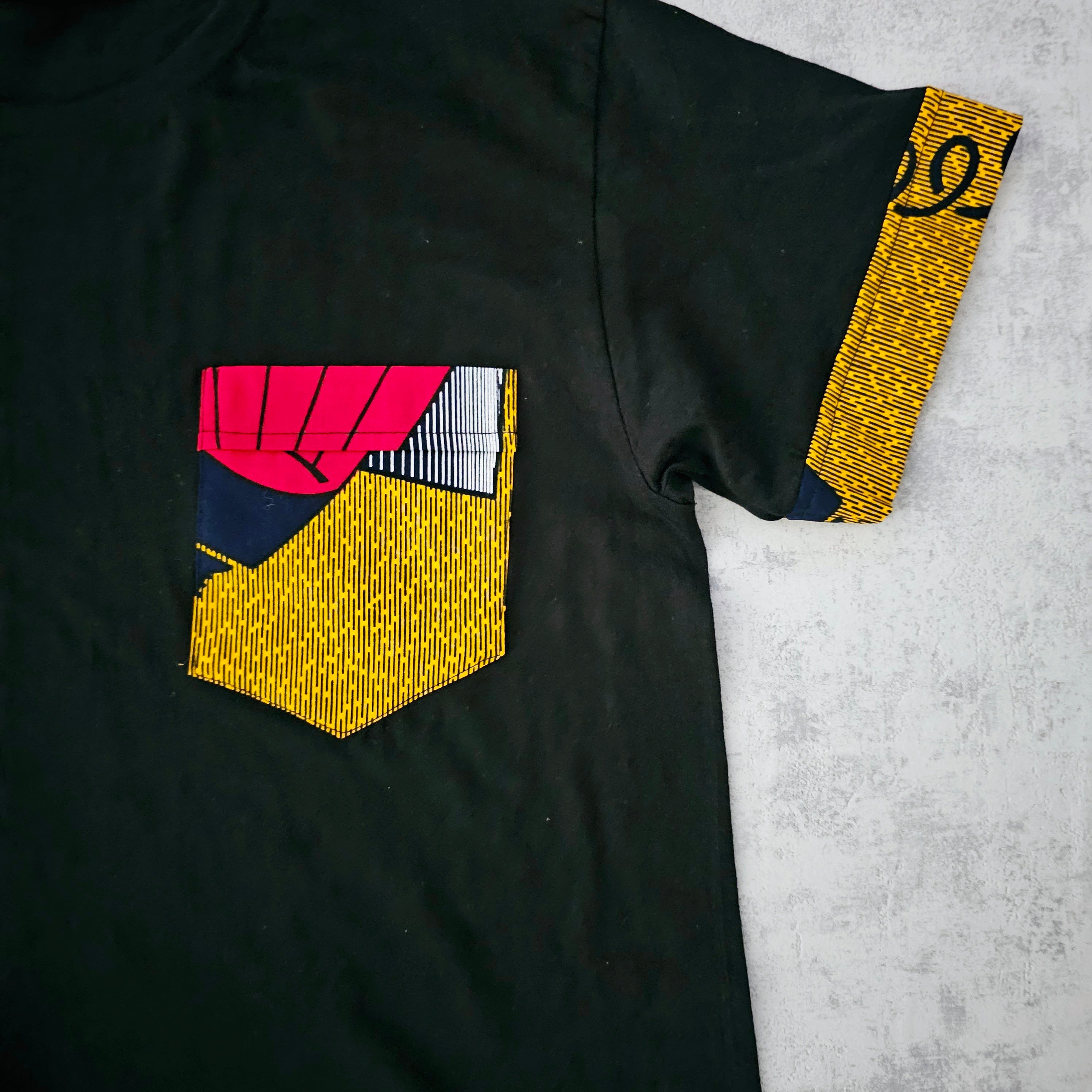 Black unisex t-shirt featuring unique Bogolan print detail and pocket, made from 100% soft cotton jersey.