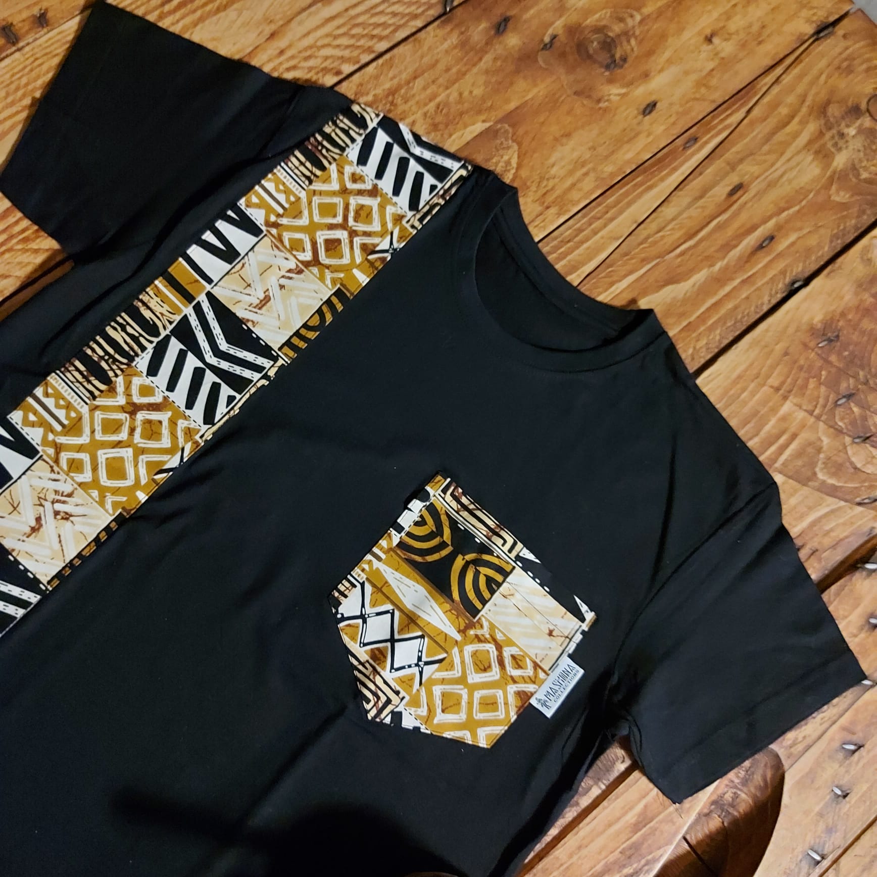 Black unisex t-shirt featuring vibrant African print detail and pocket, made from soft cotton jersey.