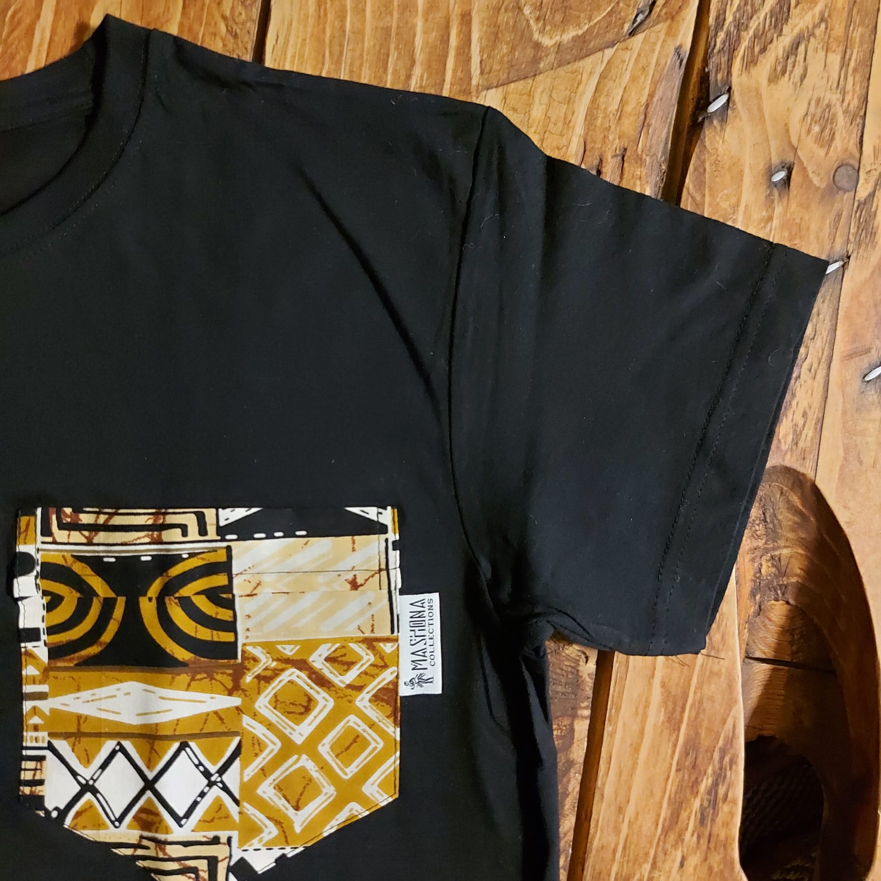Black unisex t-shirt featuring vibrant African print detail and pocket, made from soft cotton jersey.