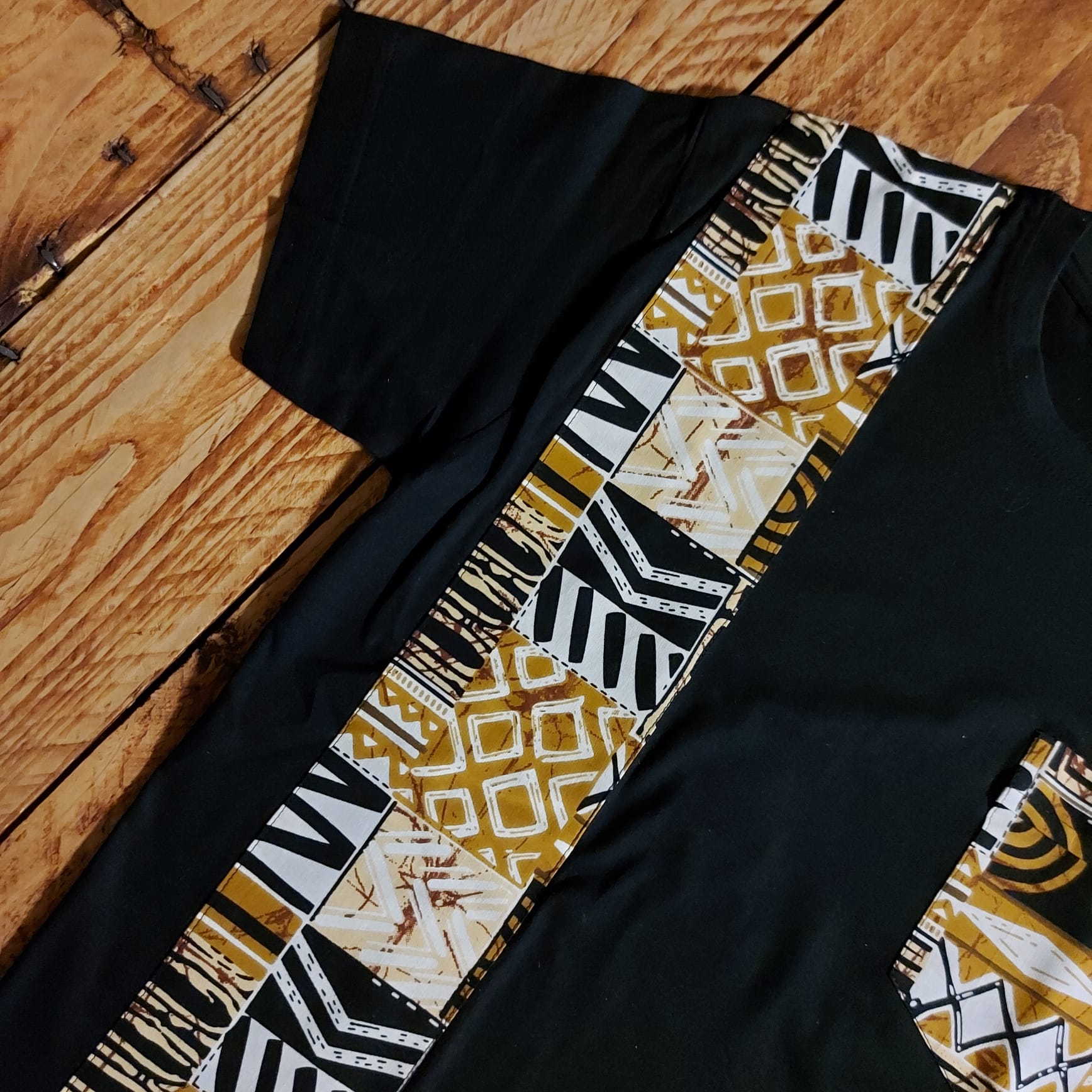 Black unisex t-shirt featuring vibrant African print detail and pocket, made from soft cotton jersey.