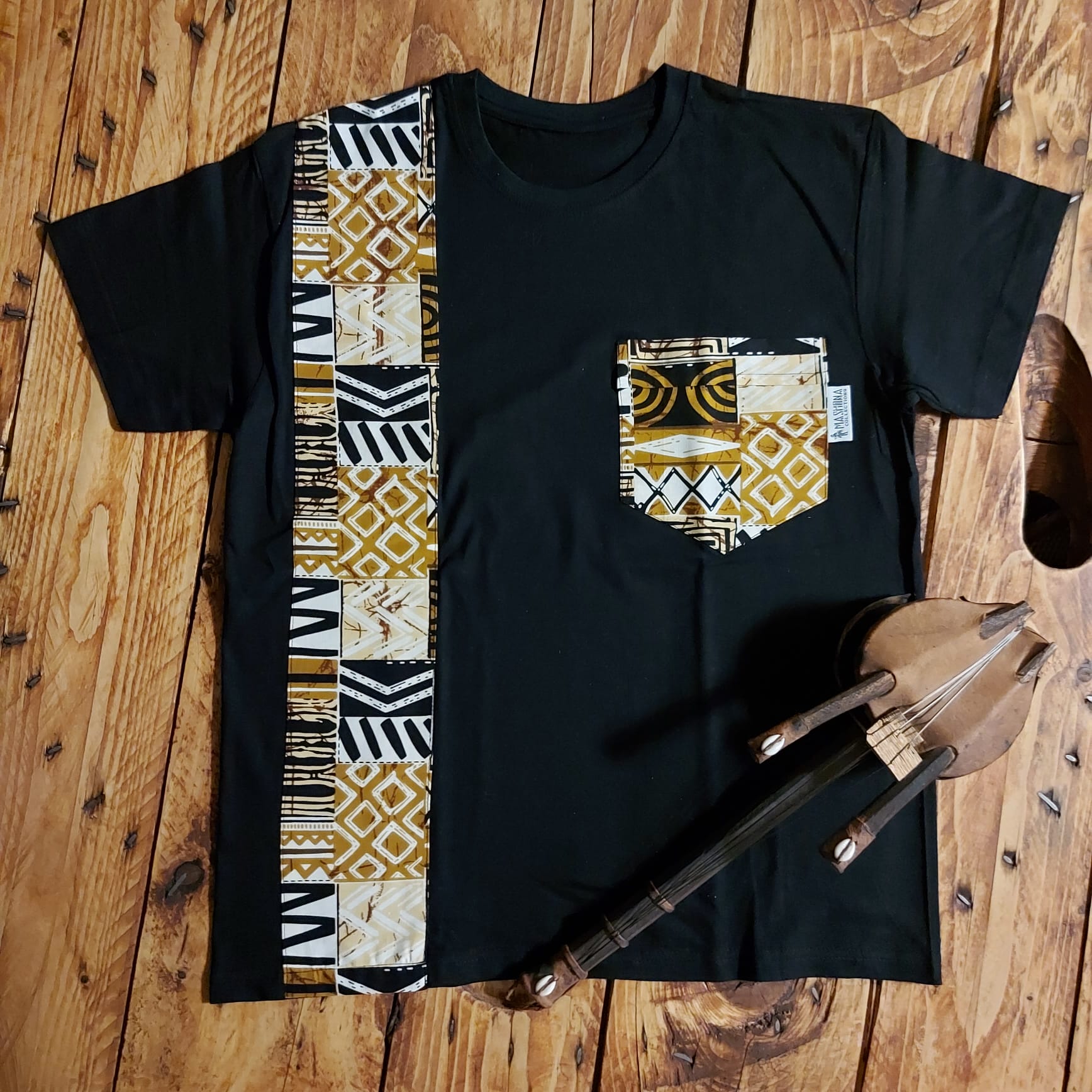 Black unisex t-shirt featuring vibrant African print detail and pocket, made from soft cotton jersey.