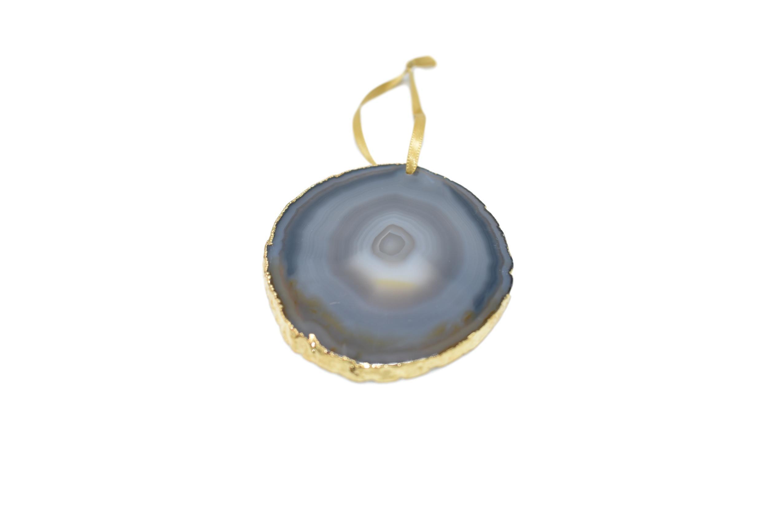 A beautiful agate ornament with gold electroplating, delicately hanging from a golden silk ribbon, showcasing unique natural patterns.