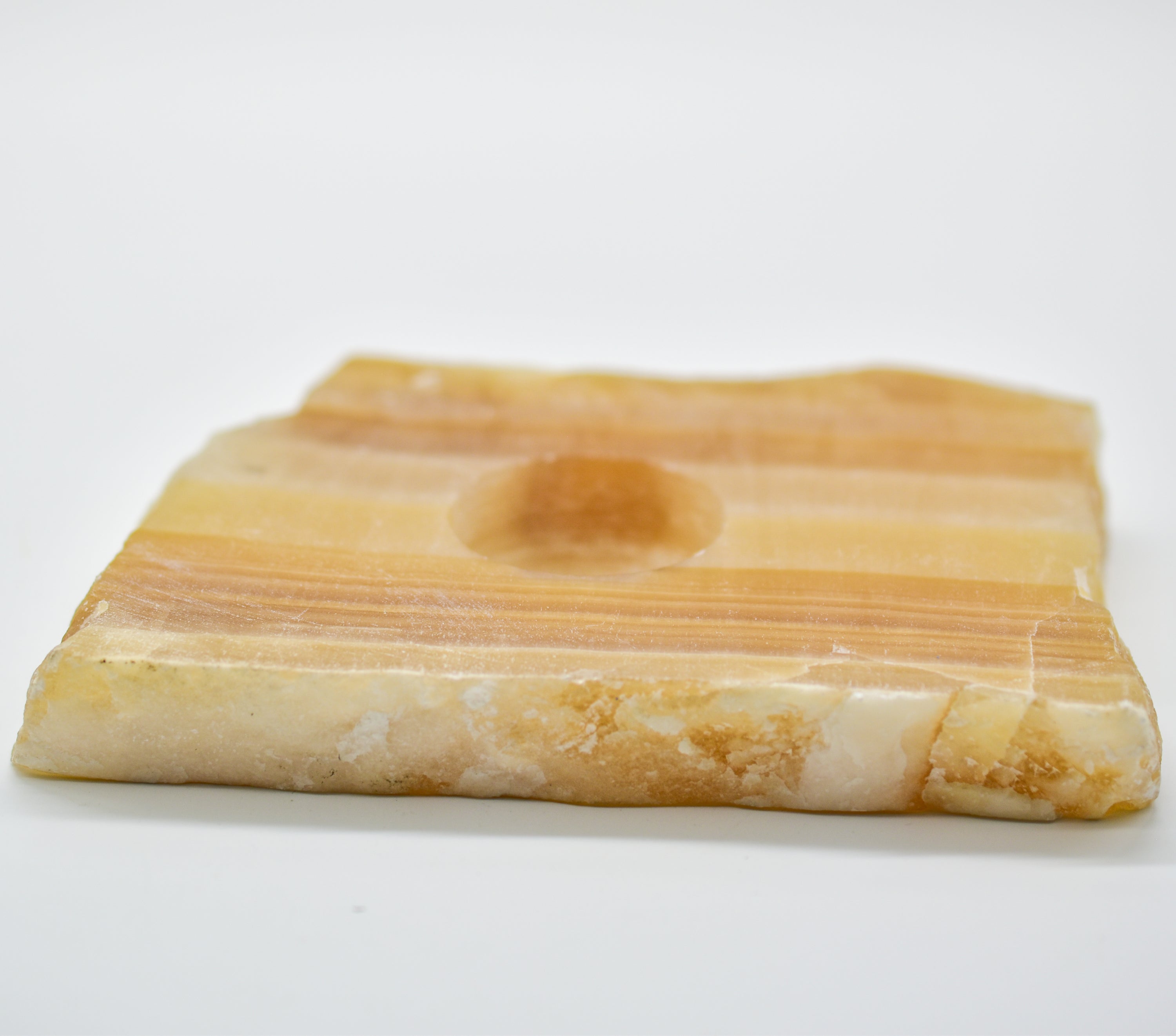 A beautifully polished Amber Onyx Slab Candle Holder showcasing unique patterns and colors, designed to hold a 1.5" tea light or votive candle.