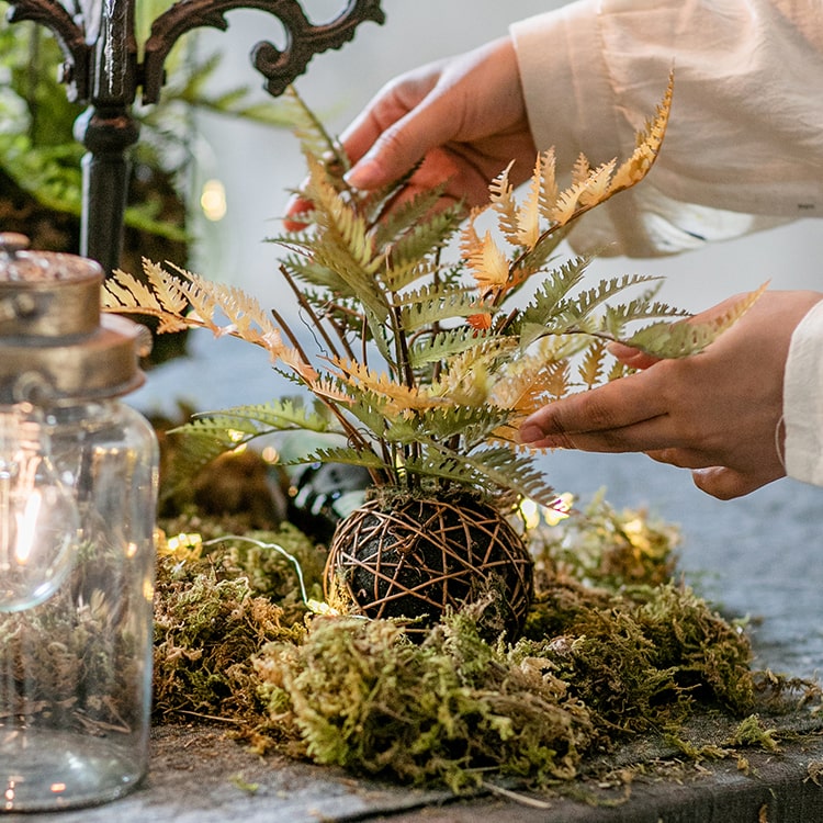 A vibrant artificial fern ball faux plant in fall colors, showcasing green, yellow, and brown hues, perfect for home decor.