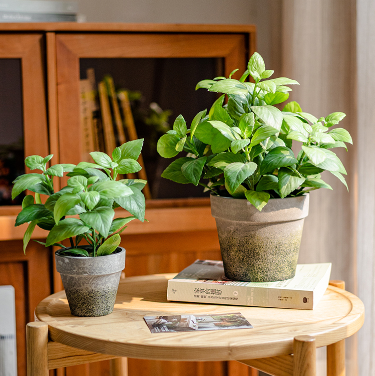 A realistic artificial potted mint plant in a gray taupe pot, showcasing vibrant green leaves.