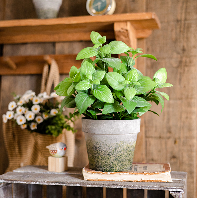 A realistic artificial potted mint plant in a gray taupe pot, showcasing vibrant green leaves.