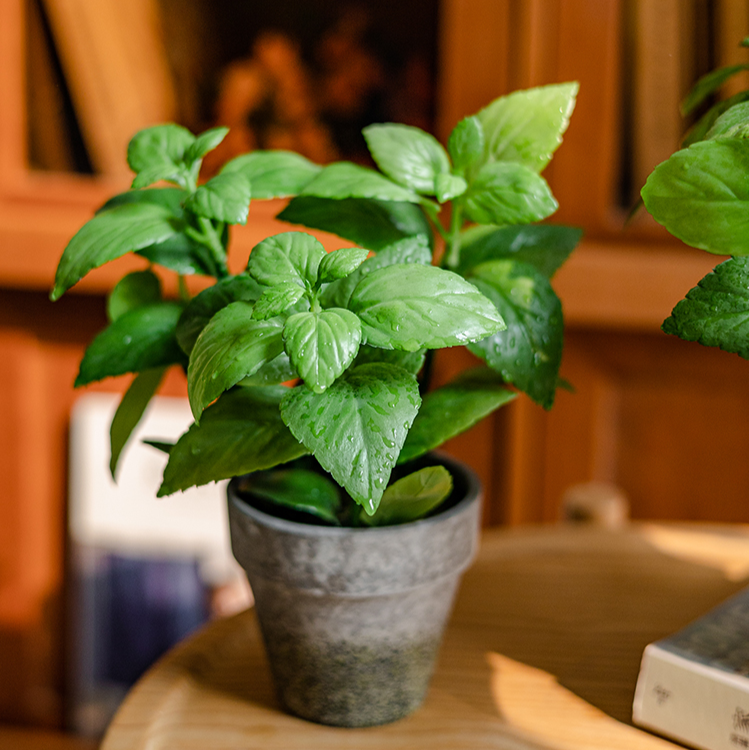 A realistic artificial potted mint plant in a gray taupe pot, showcasing vibrant green leaves.