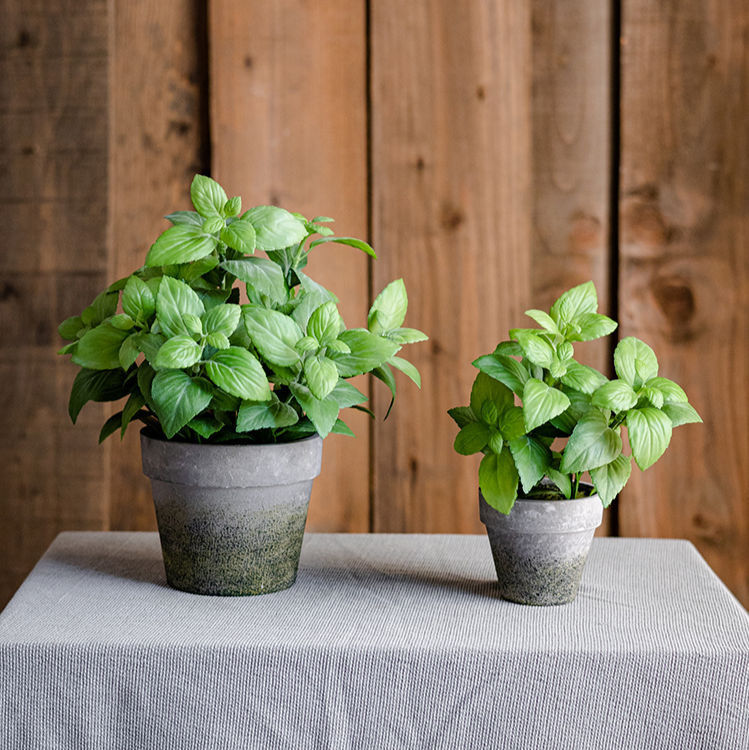 A realistic artificial potted mint plant in a gray taupe pot, showcasing vibrant green leaves.