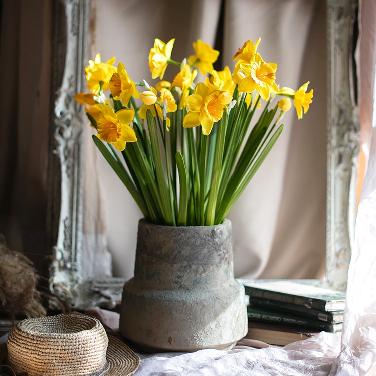 A vibrant 19-inch tall artificial silk yellow daffodil flower stem with two blooms and one bud, featuring realistic green leaves.