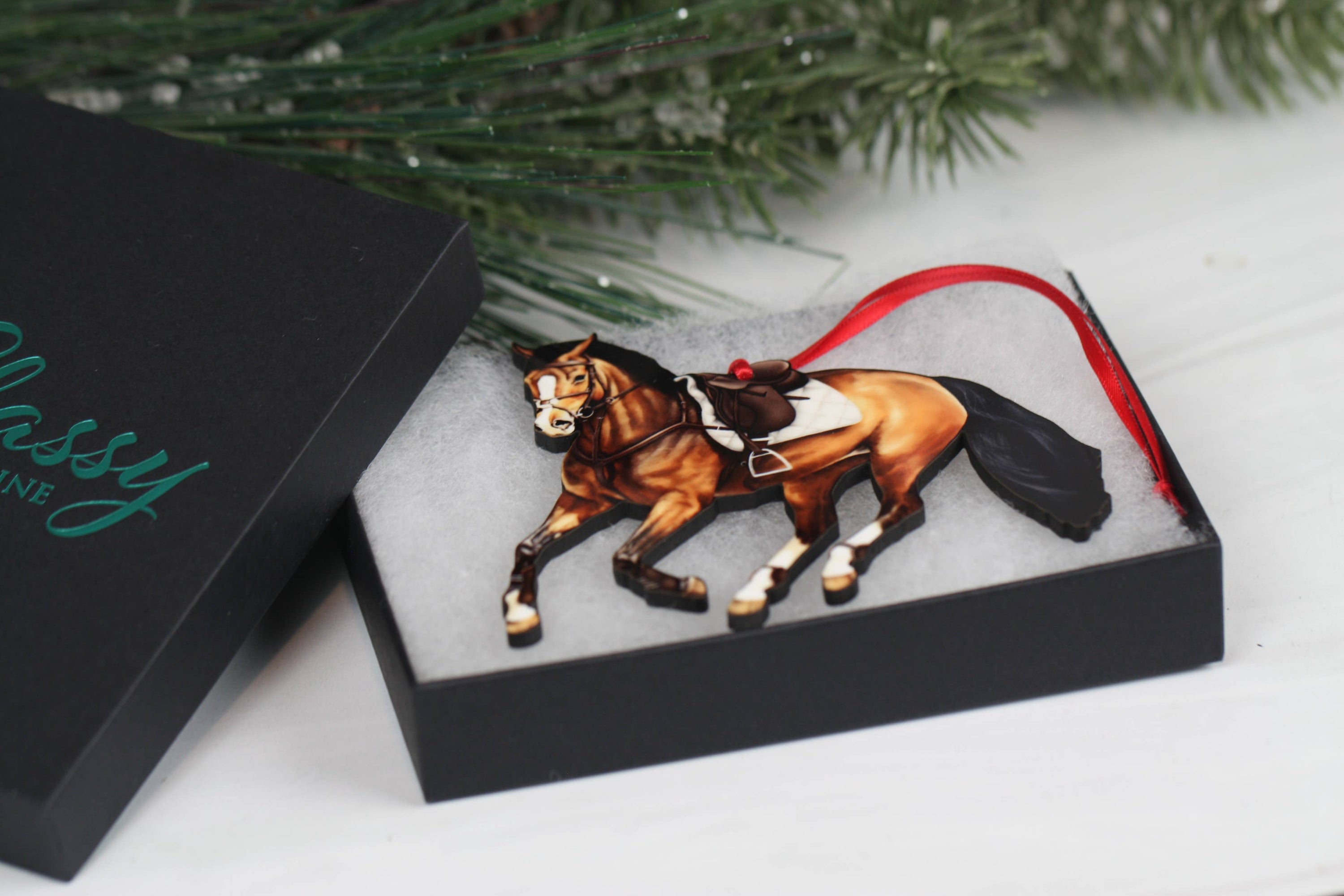 A beautifully crafted bay galloping jumper horse ornament made of composite wood, featuring red and black ribbons, perfect for Christmas and year-round display.
