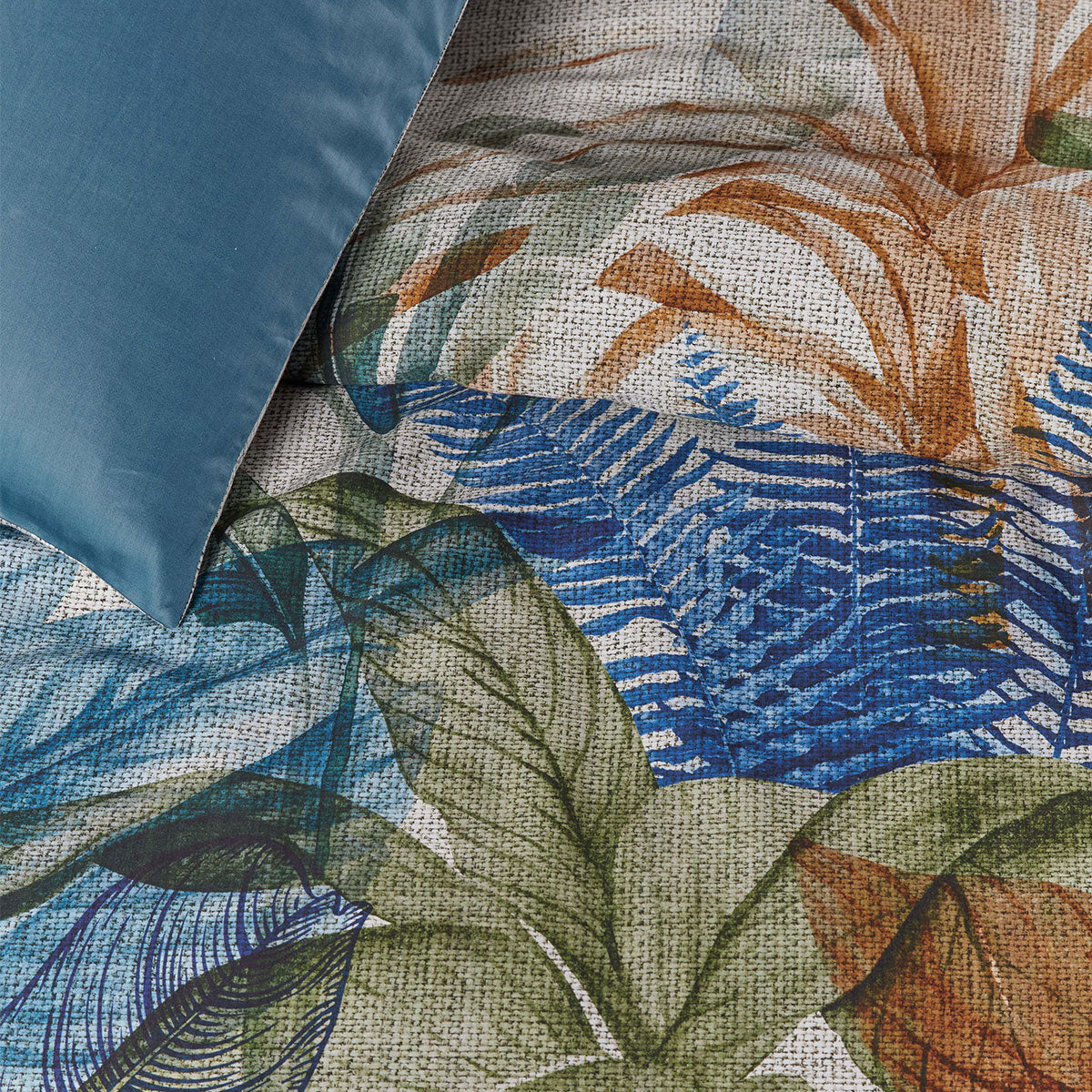 Isla Blue Cotton Sateen Quilt Cover Set featuring tropical foliage print in vibrant colors, with a soft blue backing.