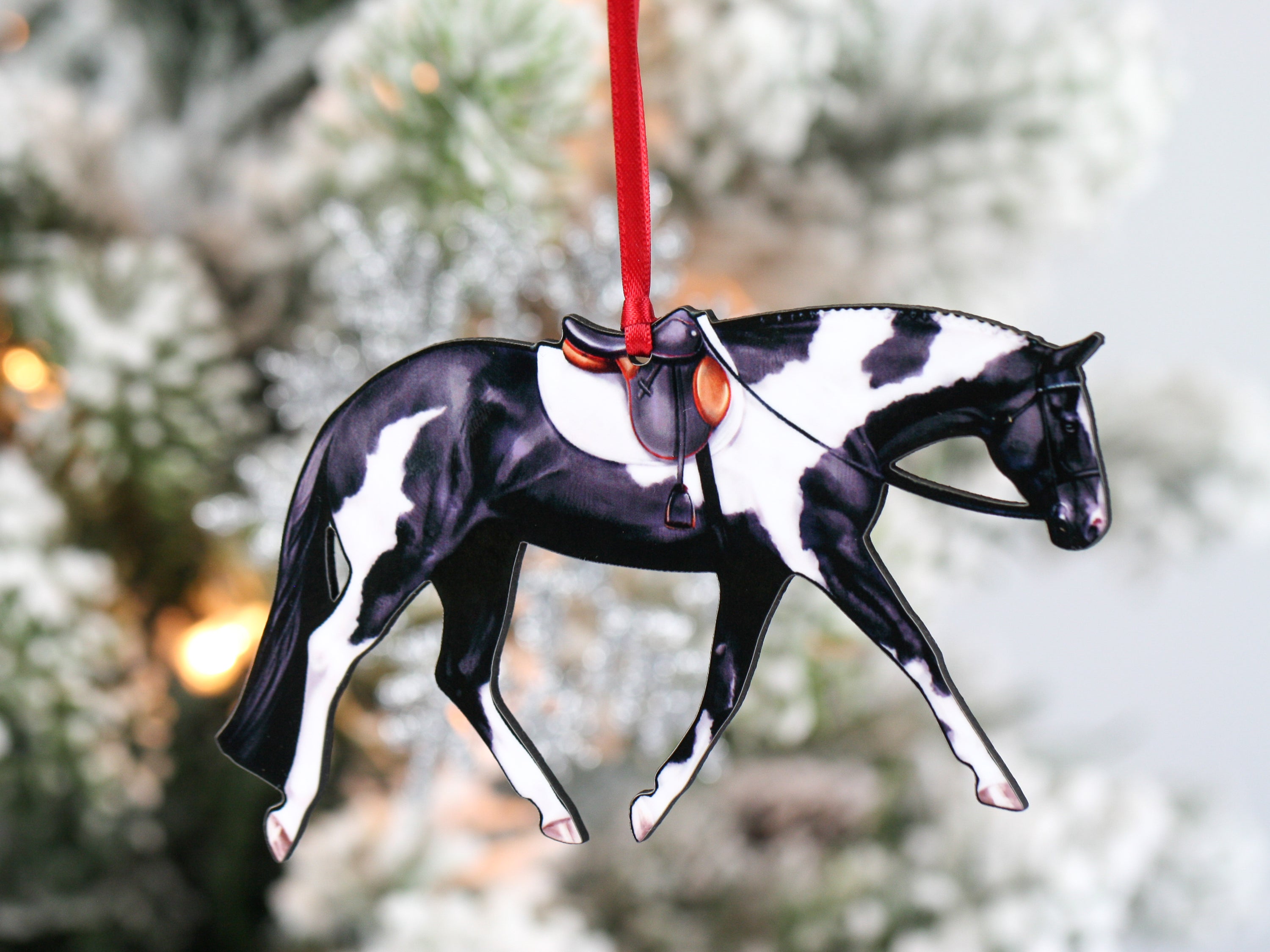 A beautifully crafted black and white tobiano Paint horse ornament with English tack, made from composite wood.