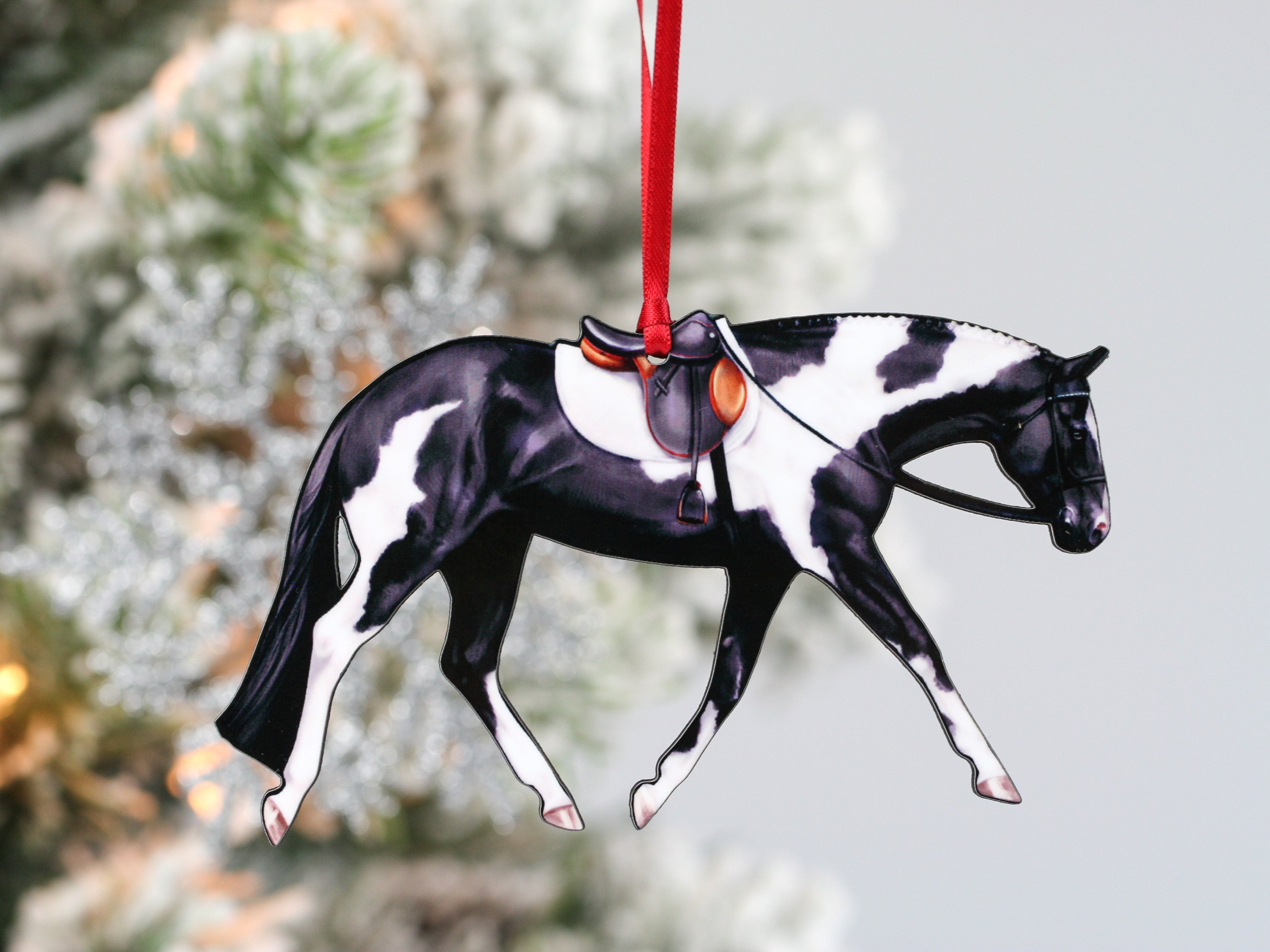 A beautifully crafted black and white tobiano Paint horse ornament with English tack, made from composite wood.