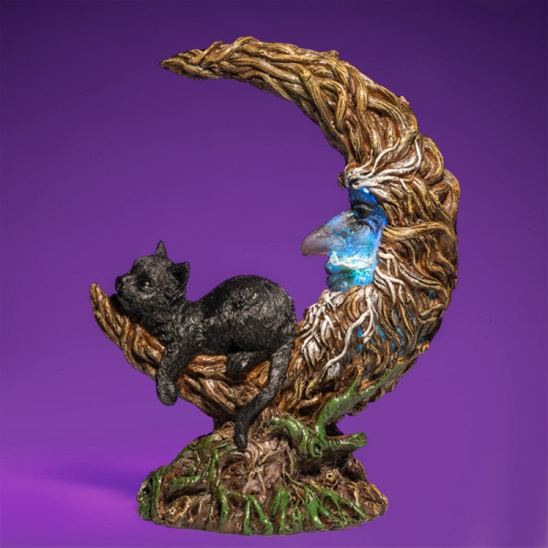 A whimsical LED light featuring a black cat sitting on a crescent moon surrounded by tree branches, casting a soft glow.