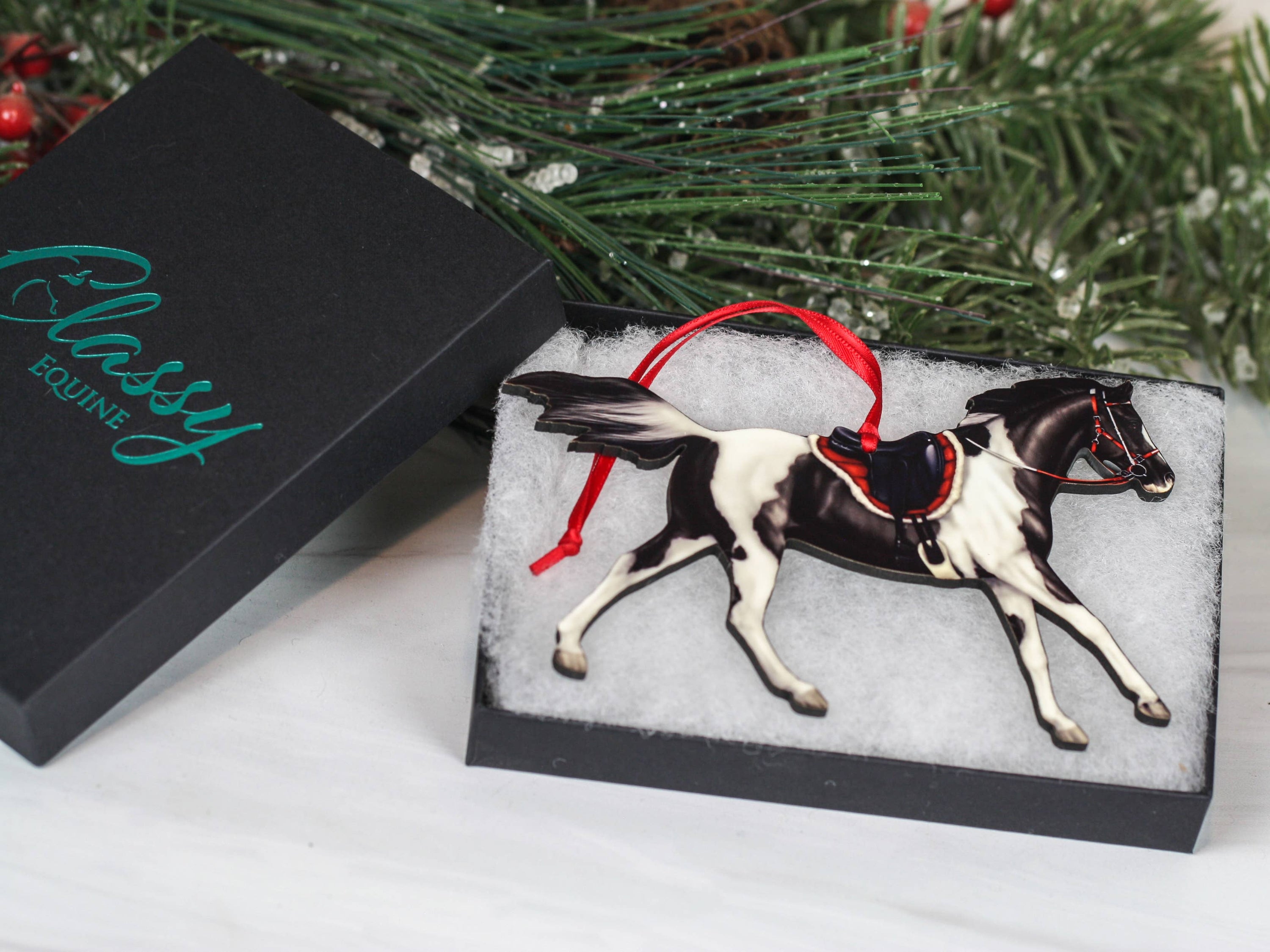 Black Tobiano Pinto Horse Christmas Ornament with red and black ribbons, showcasing a detailed laser-cut design on composite wood.