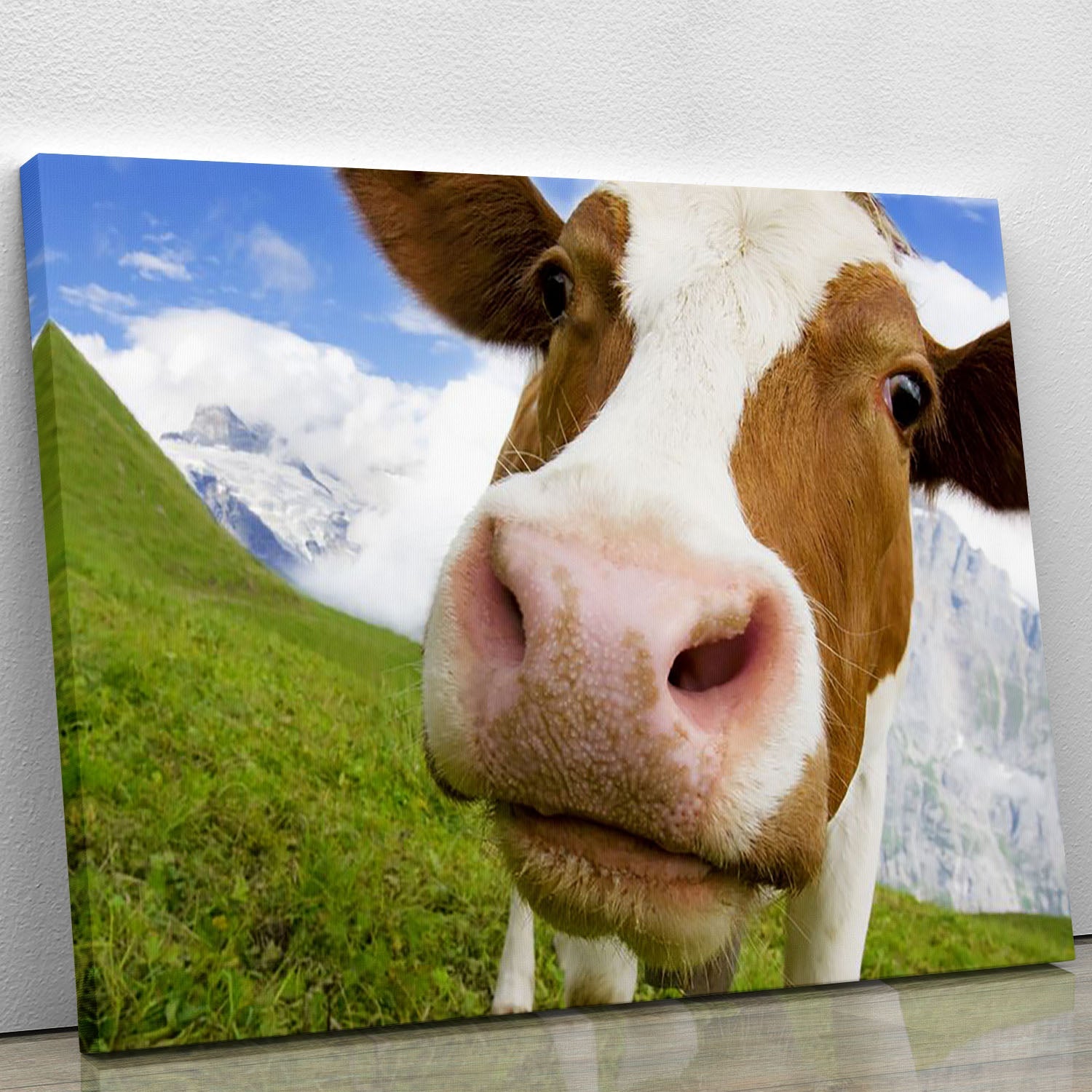 A beautiful canvas print featuring a brown and white cow in the picturesque Alps, surrounded by lush greenery and majestic mountains.