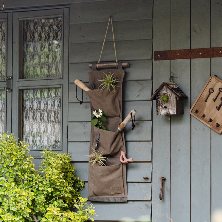 Brown canvas hanging wall storage organizer for garden tools, featuring multiple pockets and a rustic design.
