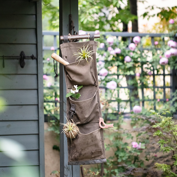 Brown canvas hanging wall storage organizer for garden tools, featuring multiple pockets and a rustic design.