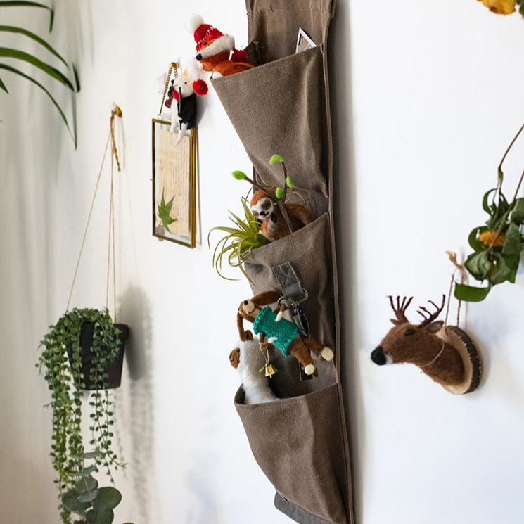 Brown canvas hanging wall storage organizer for garden tools, featuring multiple pockets and a rustic design.