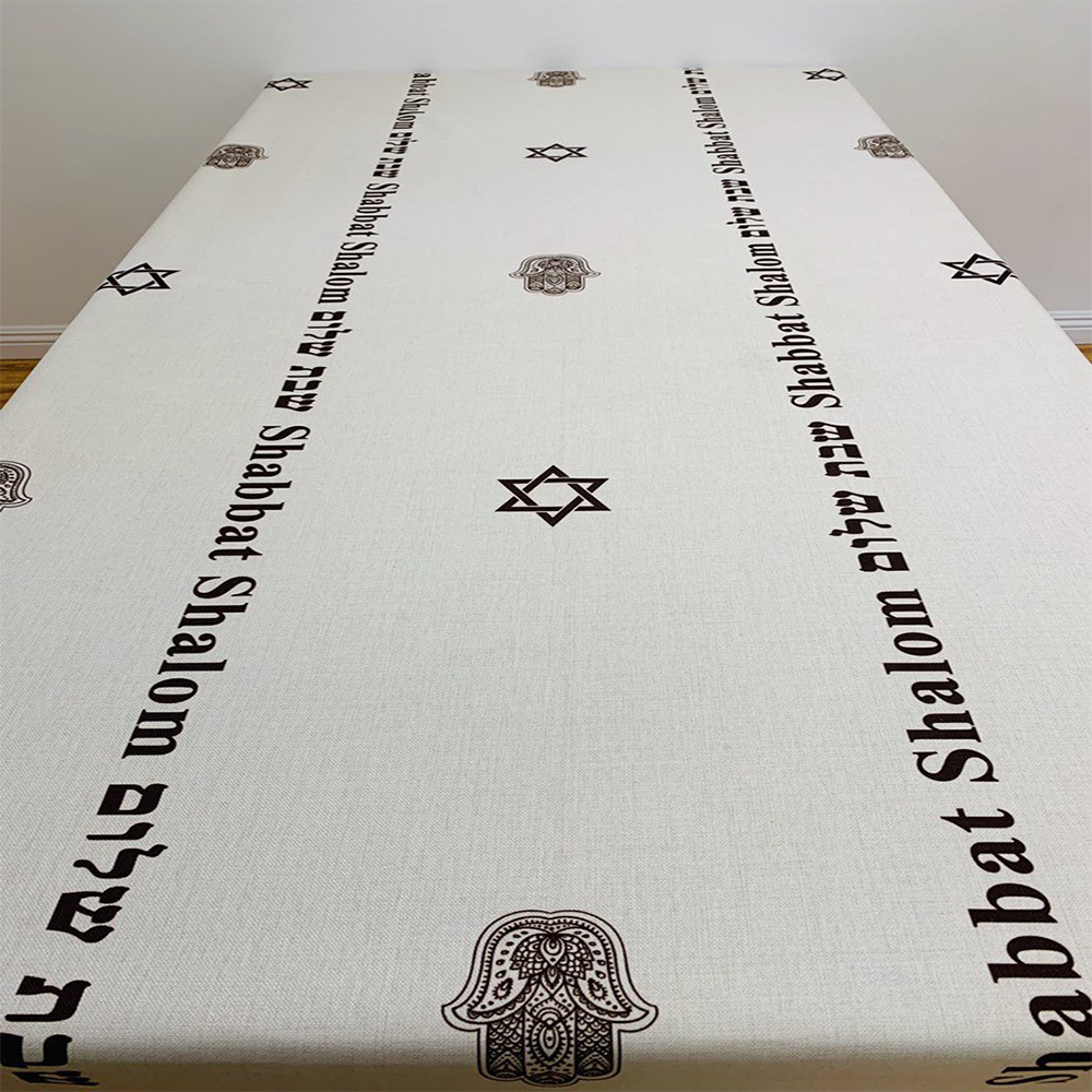 Brown Shabbat Shalom tablecloth featuring Shabbat Shalom stripes in English and Hebrew, adorned with Magen David and Hamsa details.