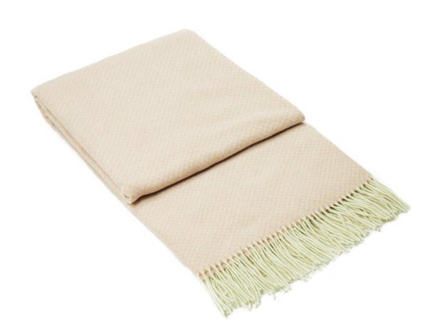 Chiswick Throw blanket in blush color, made from a luxurious merino wool and cashmere blend, elegantly draped on a cozy sofa.