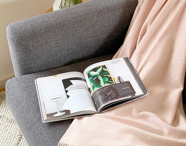 Chiswick Throw blanket in blush color, made from a luxurious merino wool and cashmere blend, elegantly draped on a cozy sofa.