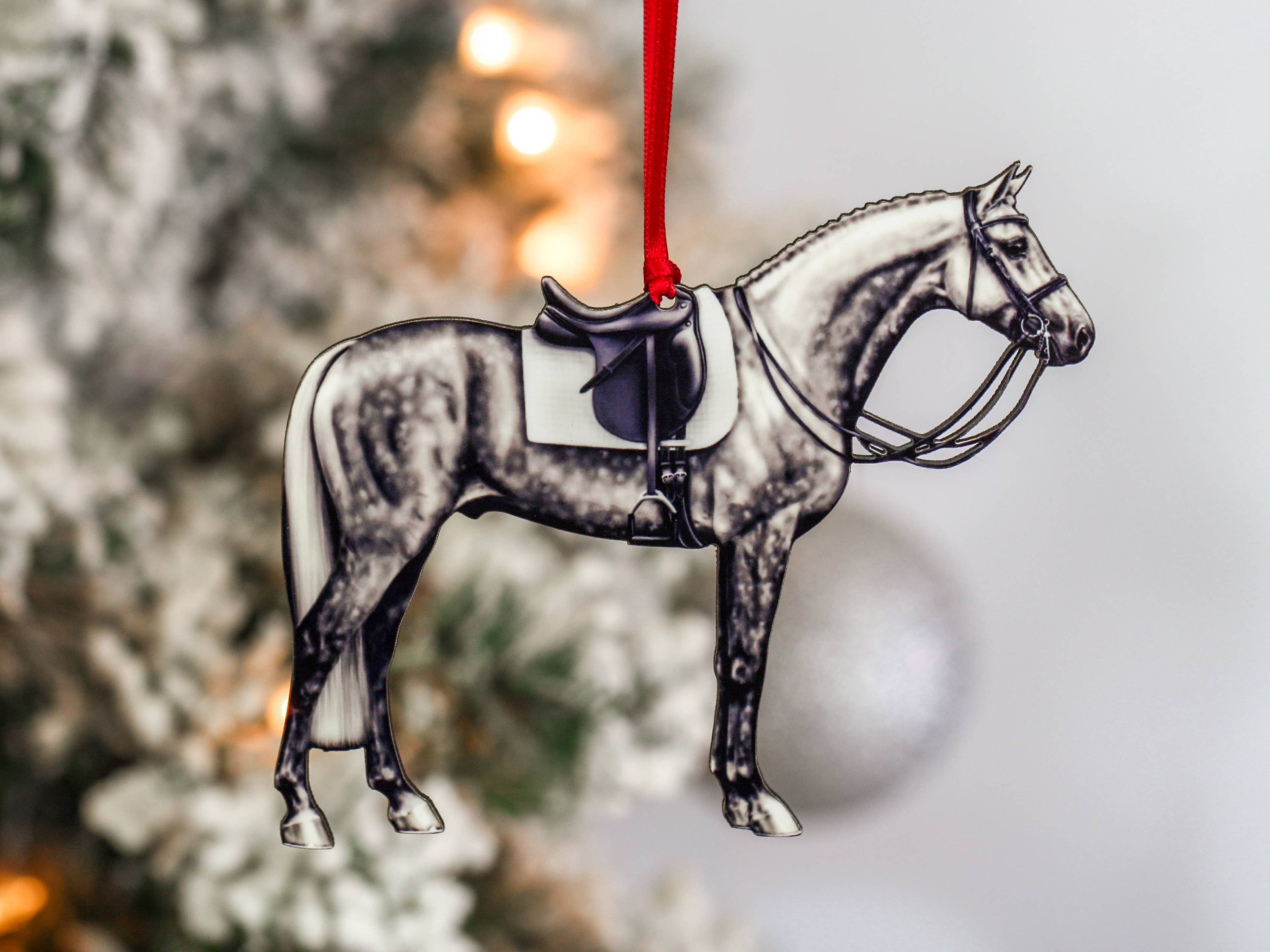 Dapple gray dressage horse Christmas ornament with red and black ribbons, handcrafted from composite wood.