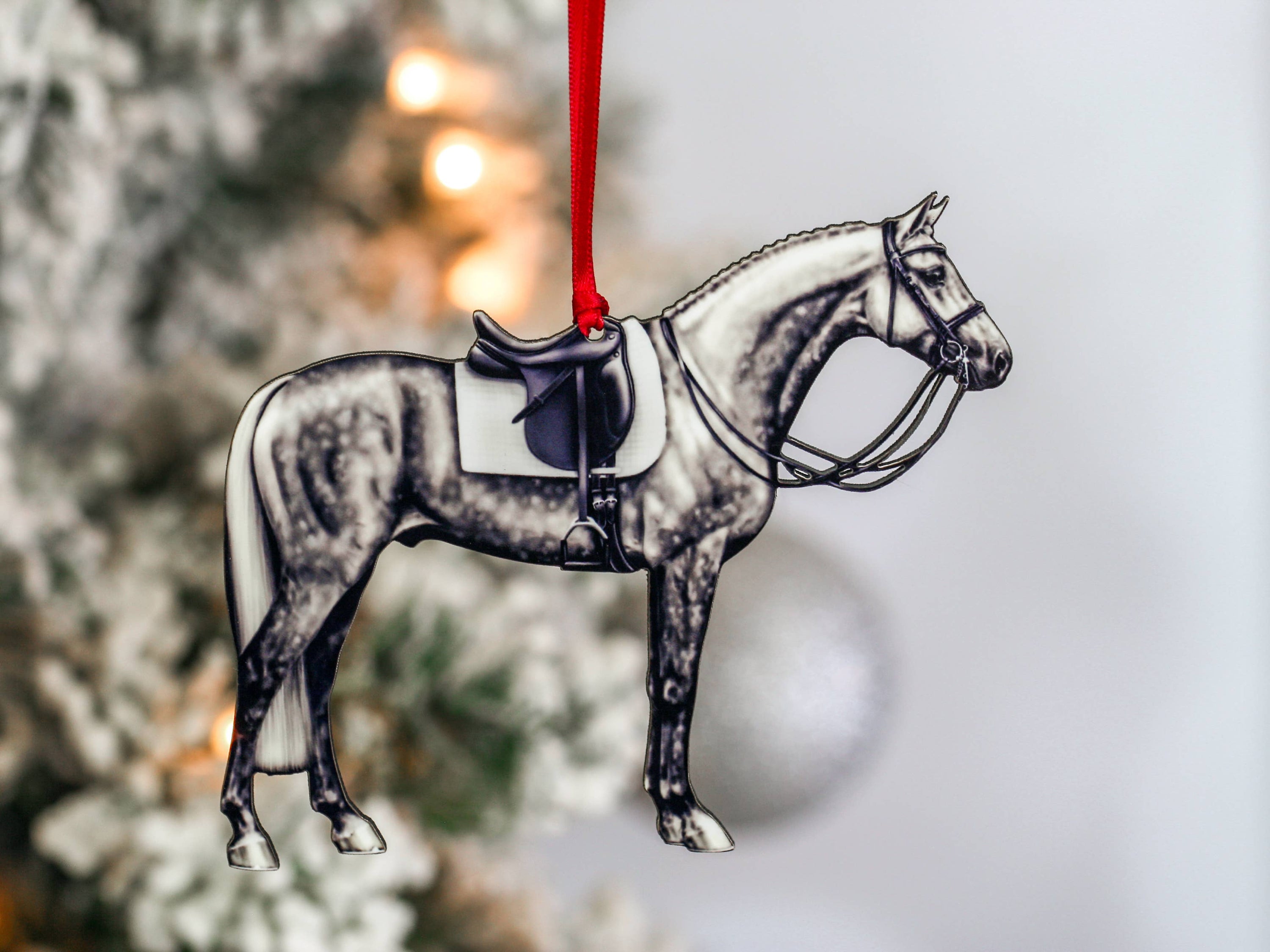 Dapple gray dressage horse Christmas ornament with red and black ribbons, handcrafted from composite wood.