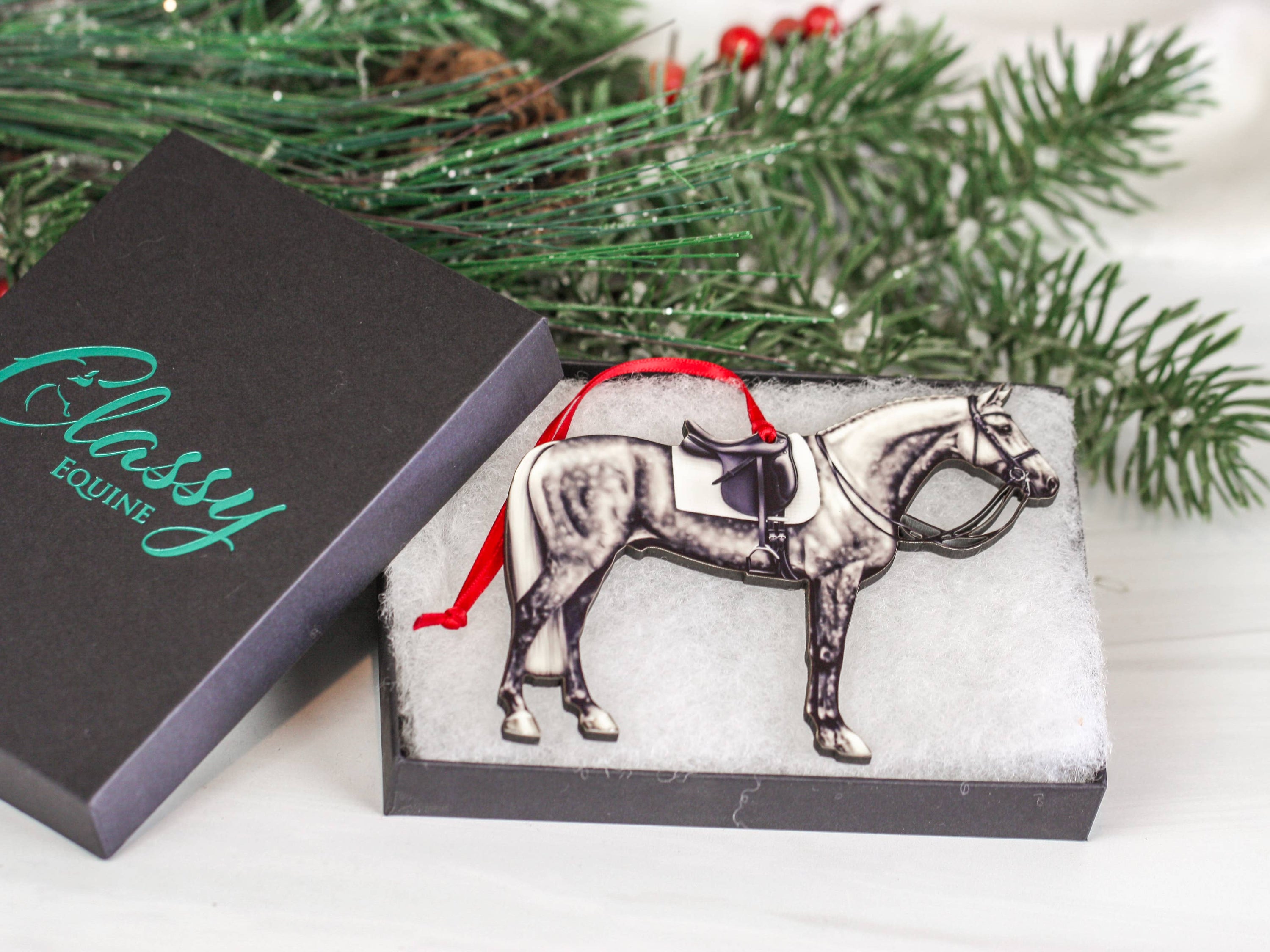 Dapple gray dressage horse Christmas ornament with red and black ribbons, handcrafted from composite wood.