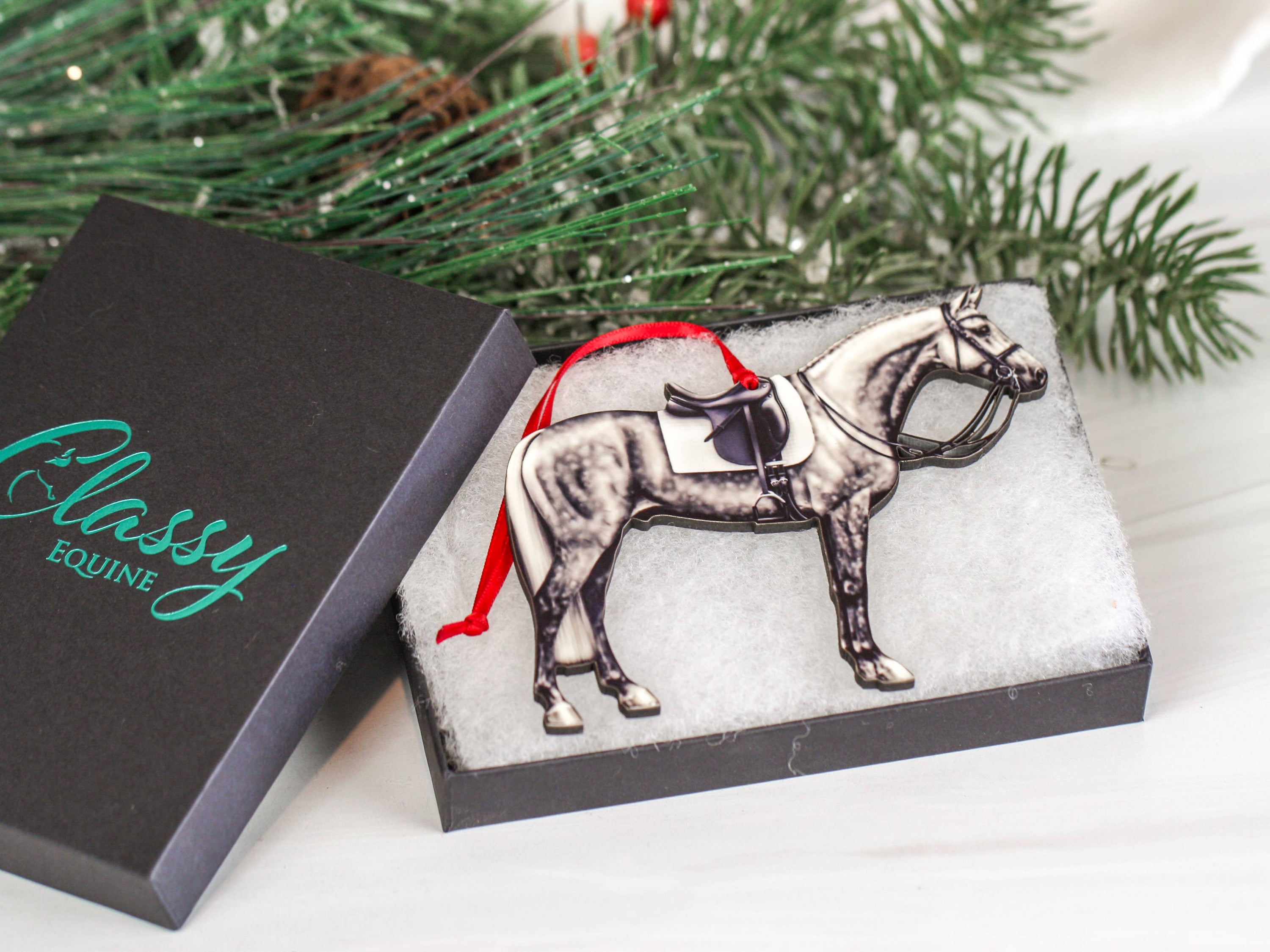Dapple gray dressage horse Christmas ornament with red and black ribbons, handcrafted from composite wood.