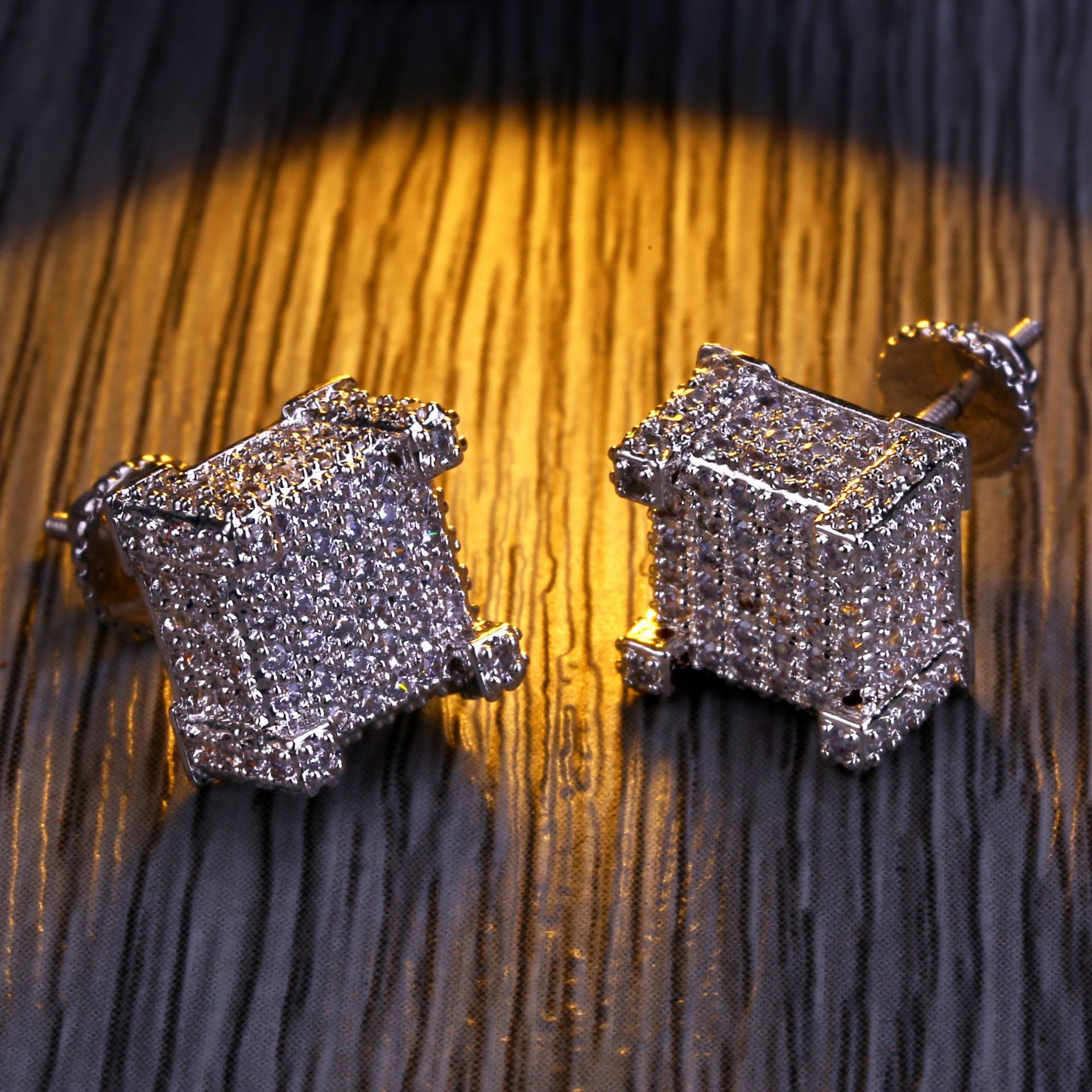 A pair of luxurious designer hip hop earrings featuring sparkling cubic zirconia stones set in a gold-plated design, perfect for stylish men.