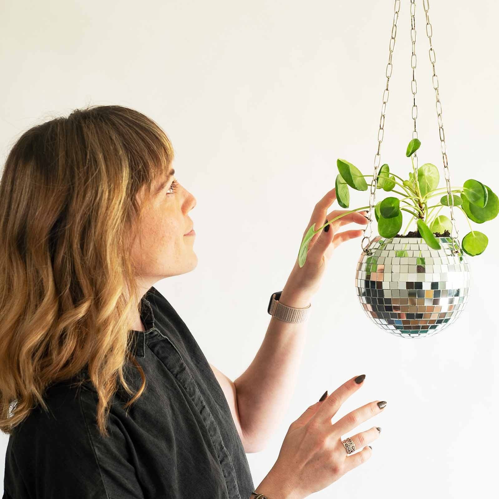 A stylish Disco Ball Planter hanging with vibrant houseplants, reflecting light and adding retro charm to the decor.