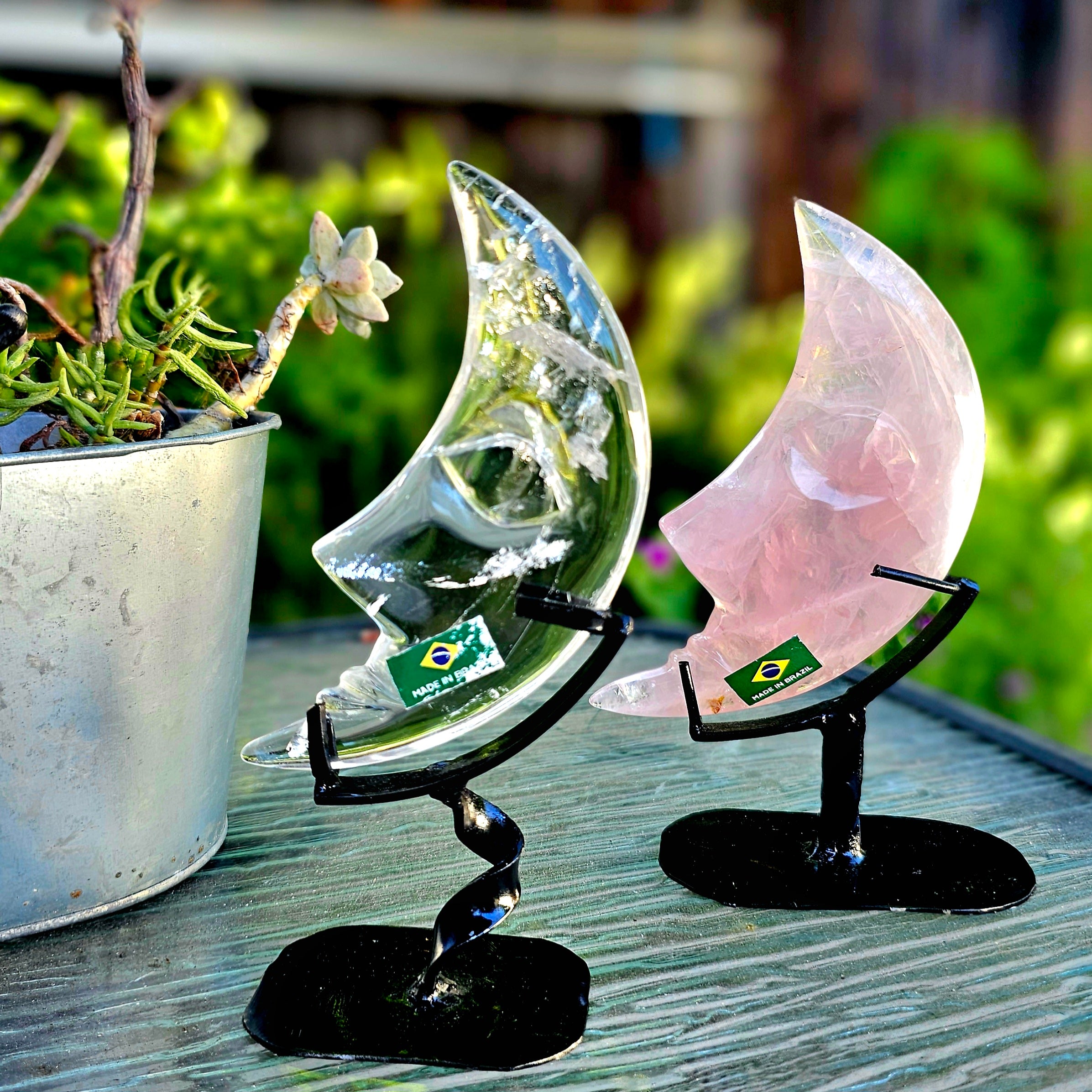 A beautifully hand-carved crescent moon made of quartz and rose quartz, mounted on a stylish twisted metal base, showcasing intricate details.